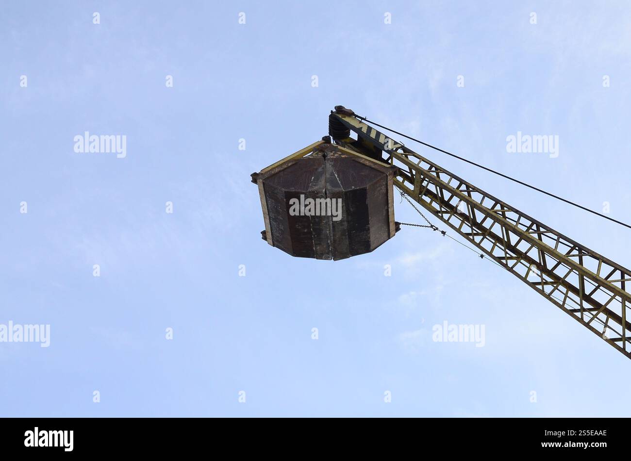 Old yellow mechanical clamshell grab on blue sky background Stock Photo