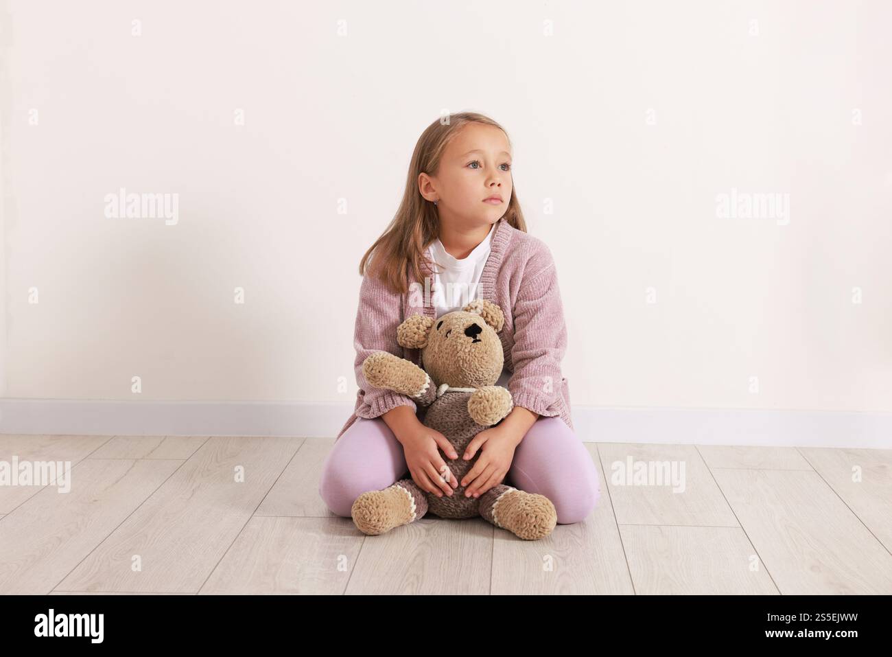 Autism concept. Lonely little girl with teddy bear on floor at home ...