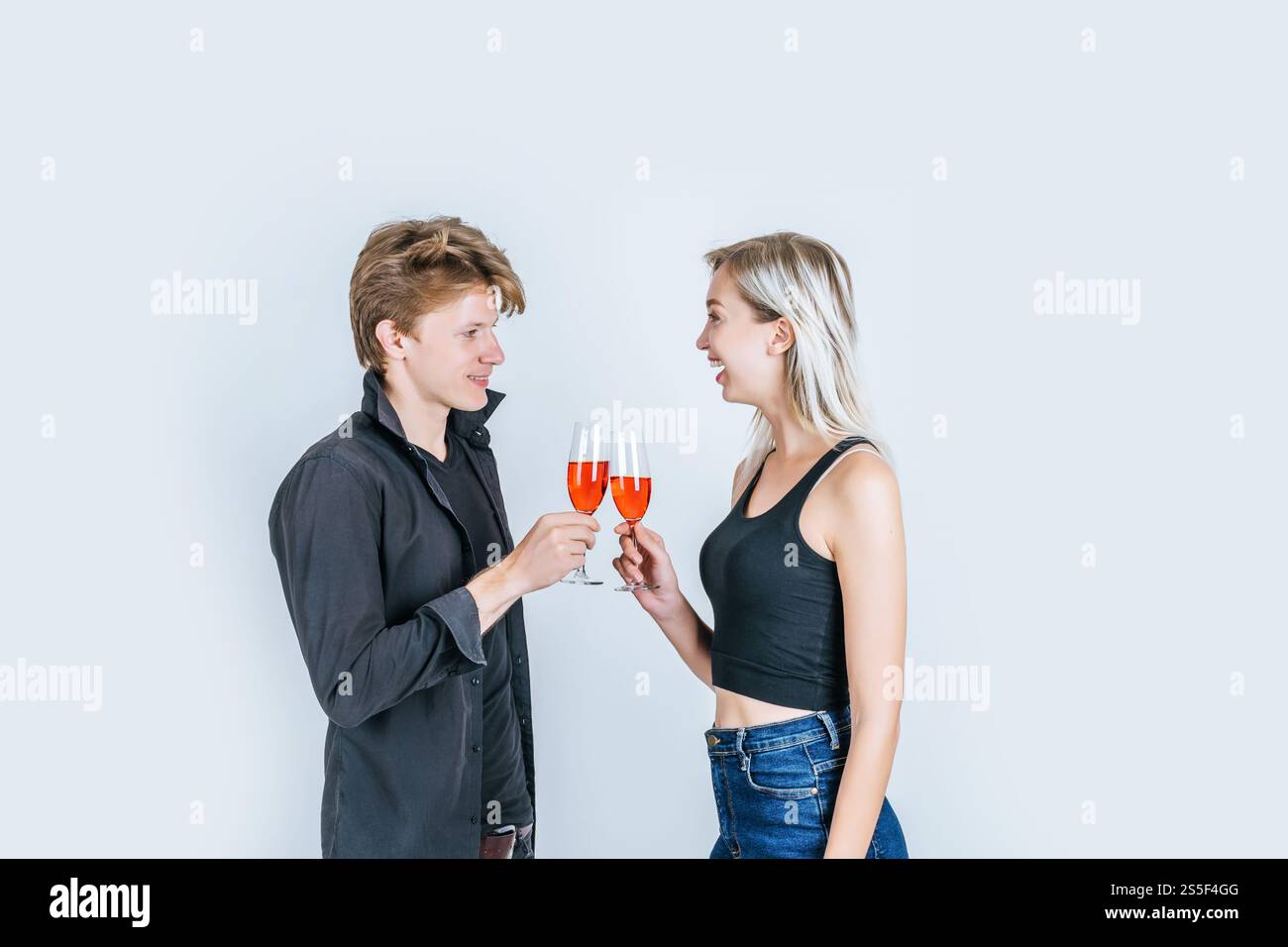 Portrait of happy young couple drinking wine in studio Stock Photo