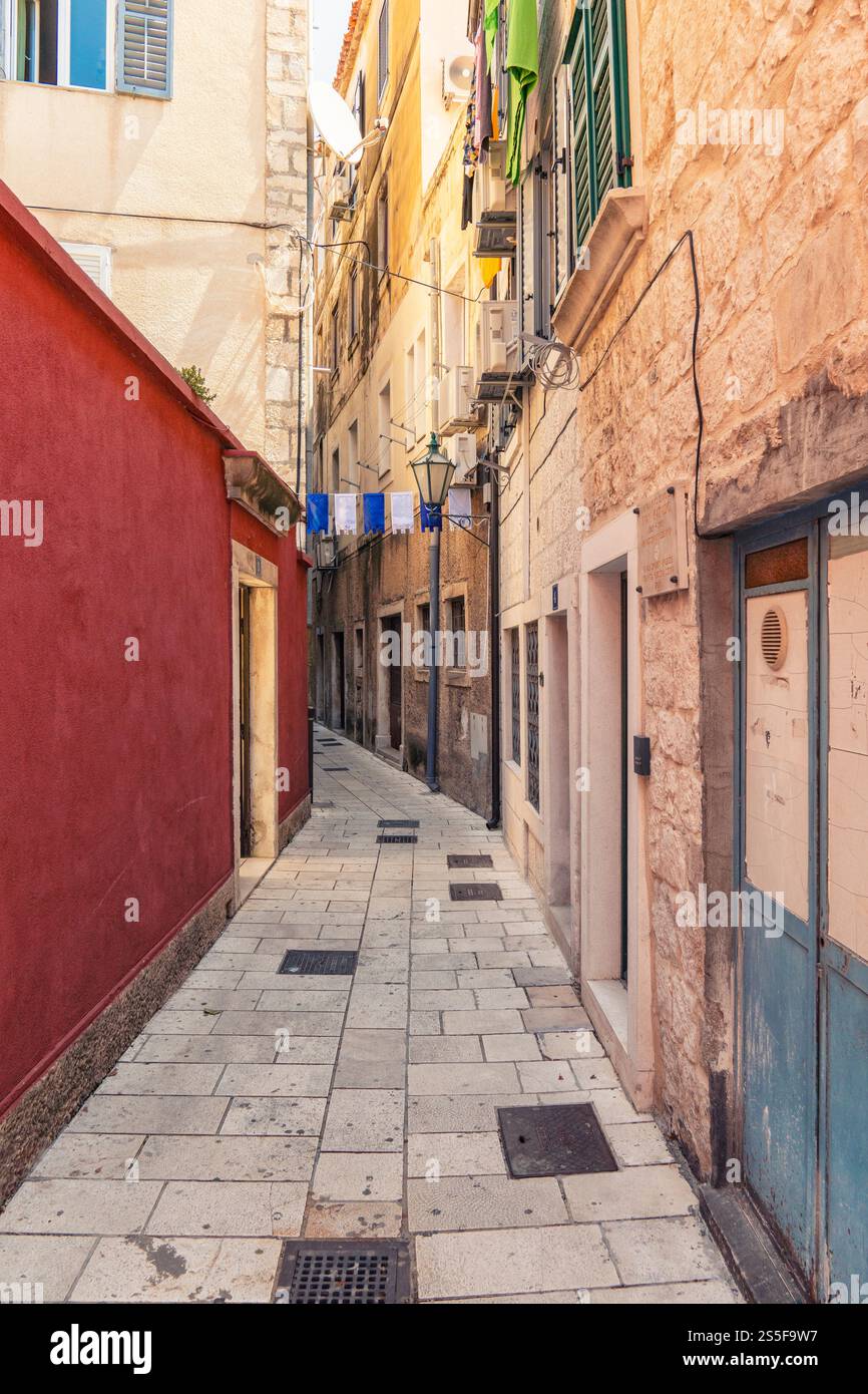Narrow alleyway with old stone buildings and hanging laundry in a European town of Omis on the Adriatic Sea, Croatia Stock Photo