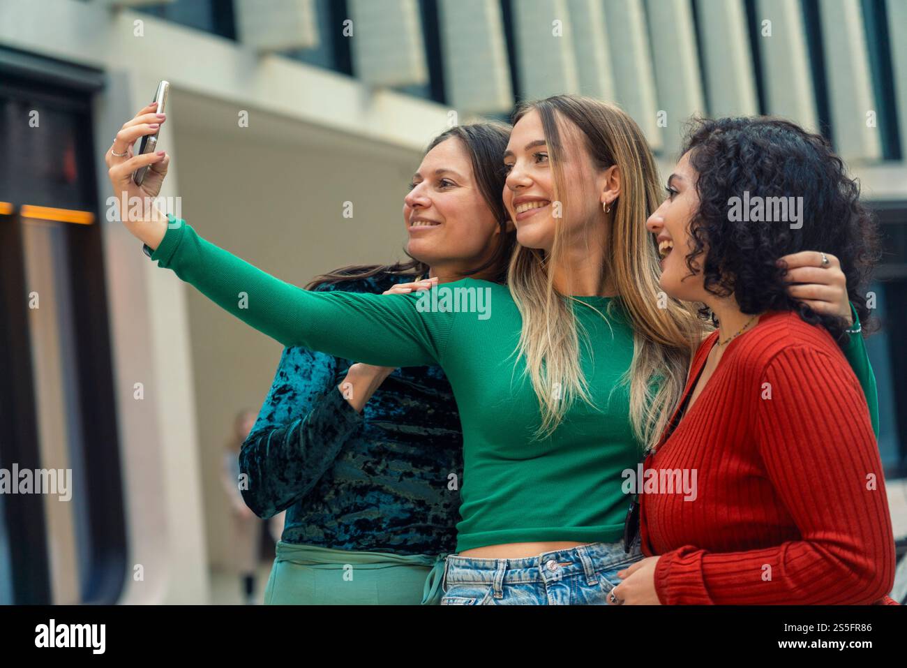 Three smiling women taking a selfie together on a city street, Berlin ...