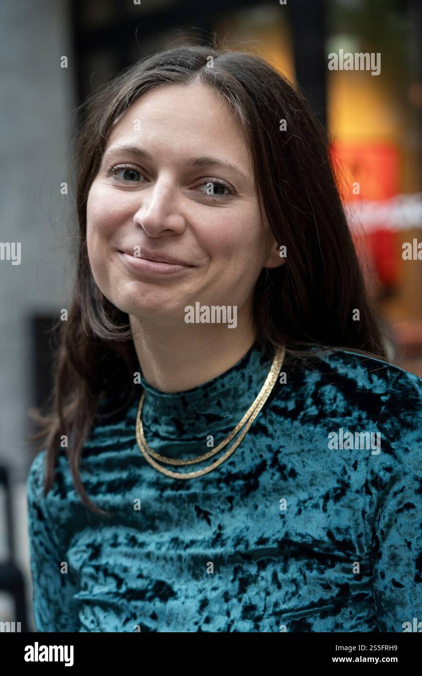 Smiling woman with long hair in a turquoise patterned top and gold ...