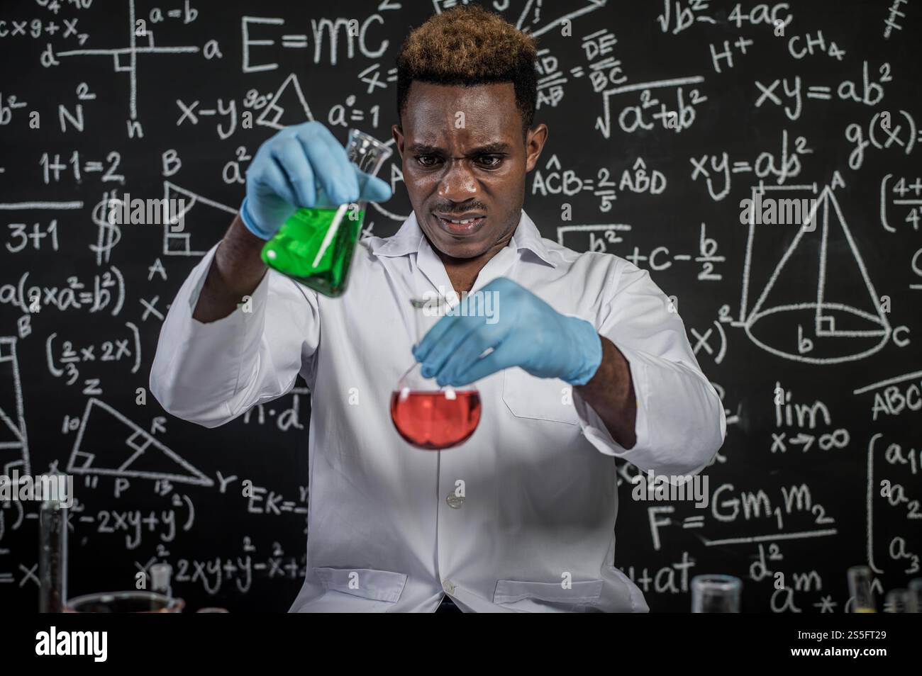 Scientists hold beakers with green and red chemicals and stressed faces. Stock Photo