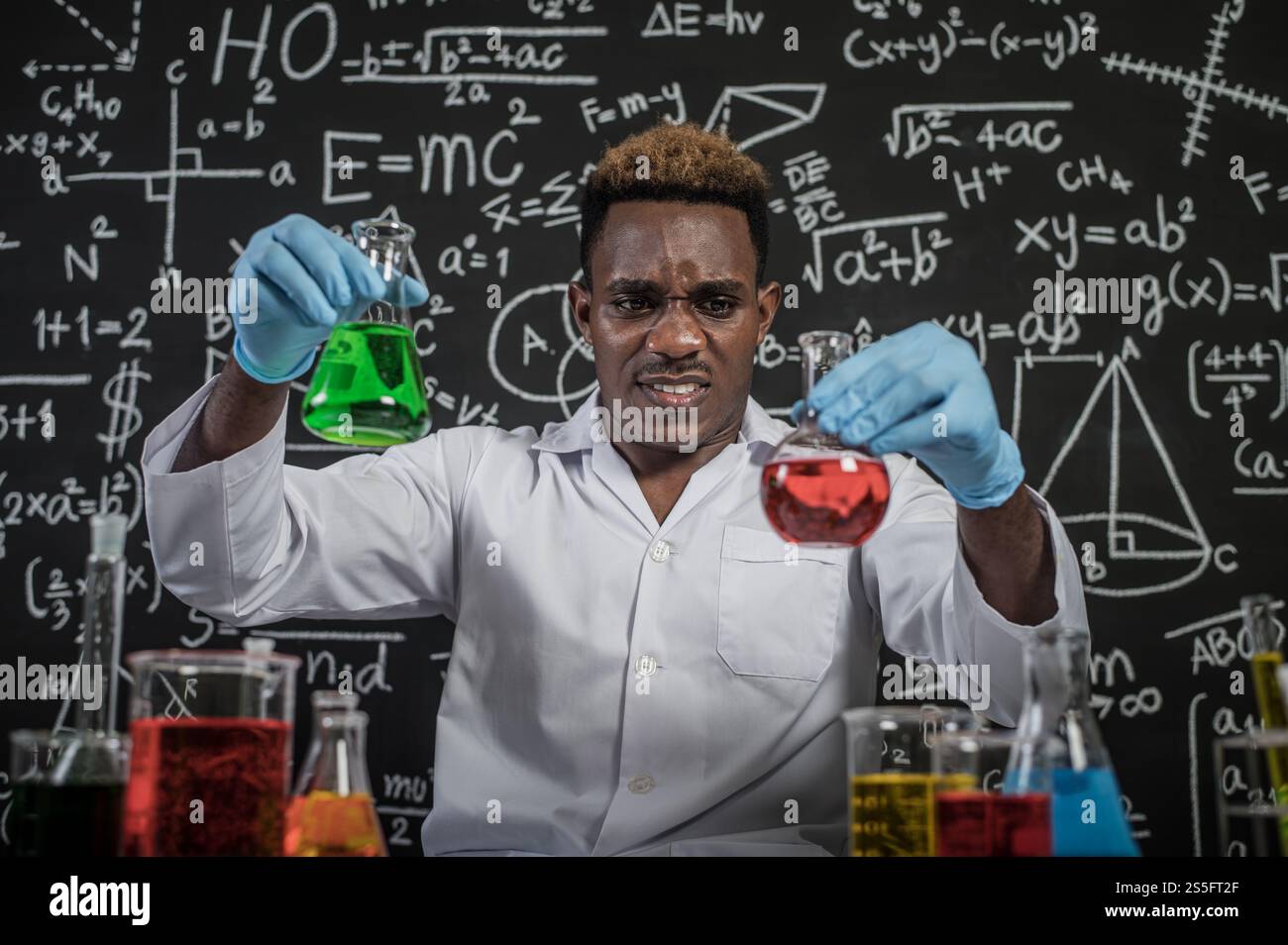 Scientists hold beakers with green and red chemicals and stressed faces. Stock Photo