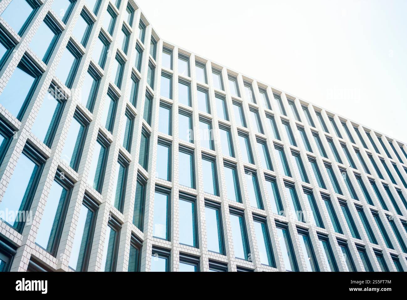 Modern architectural facade of a high-rise building with repeating patterns of windows and a clear blue sky in the background, Berlin, Germany Stock Photo