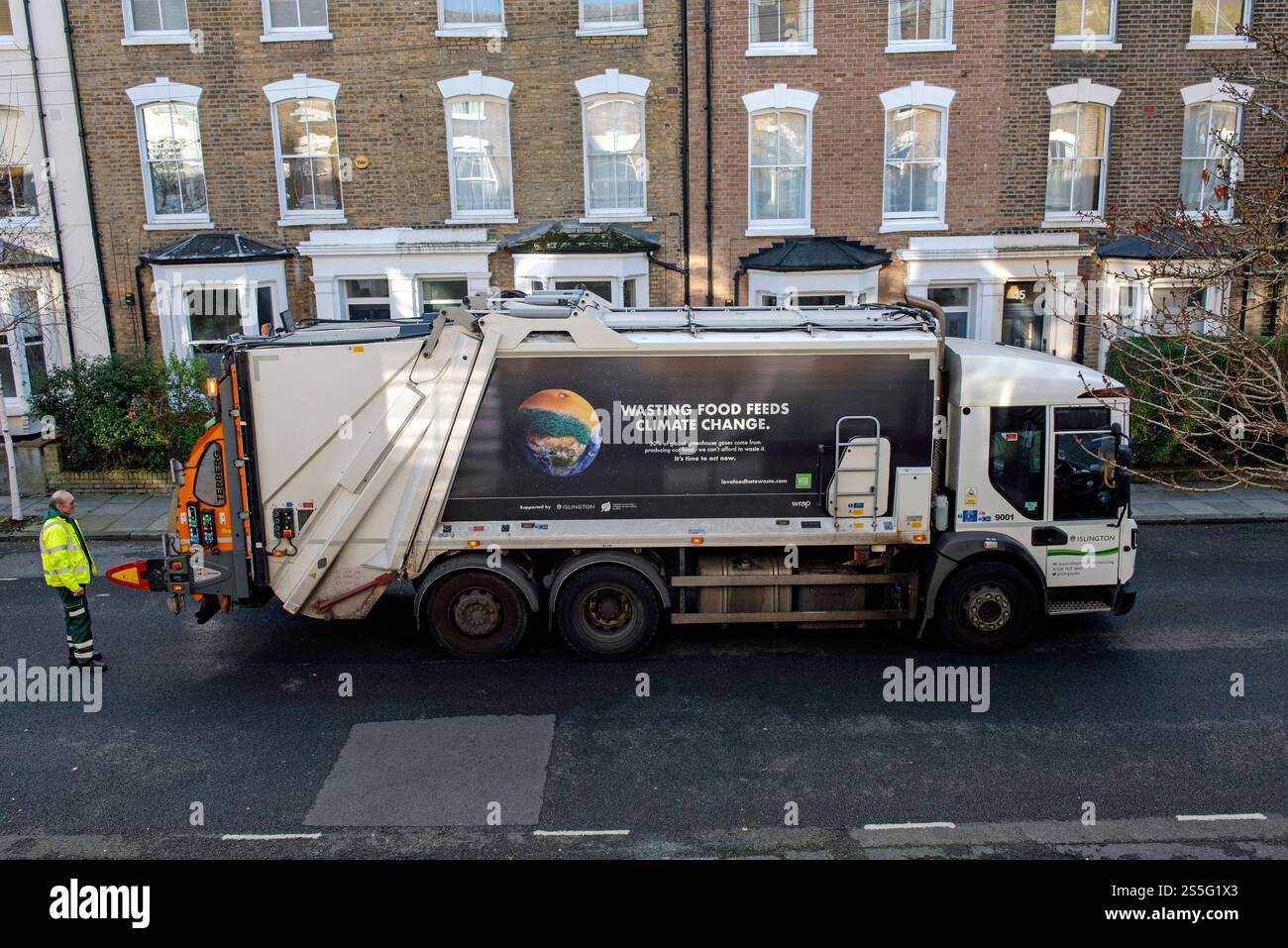 Rubbish Collection Lorry with bin man or refuse collector behind and slogan on side saying Wasting Food Feeds Climate Change. Houses behind.  Holloway Stock Photo