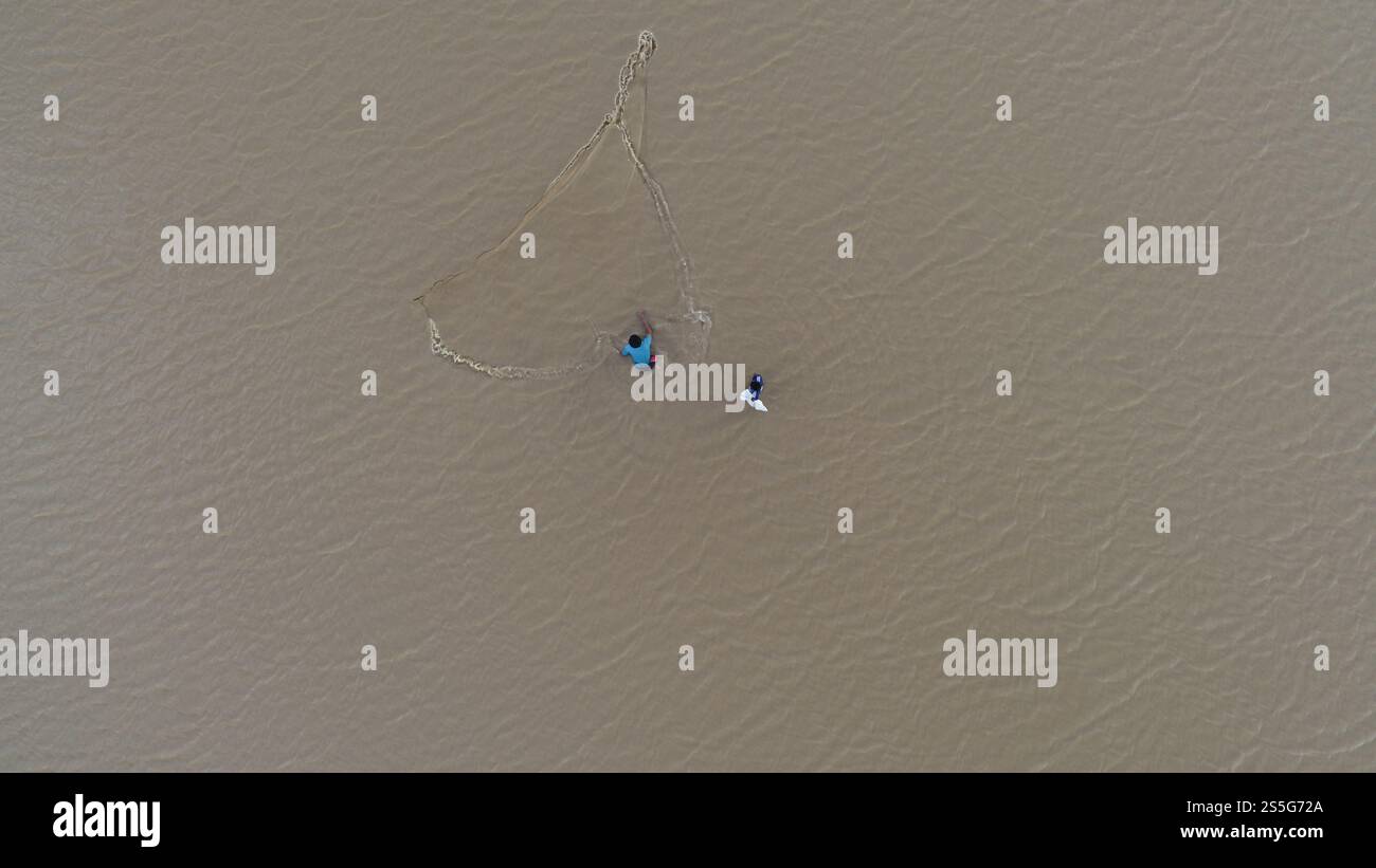 Man standing in the river trying to catch fish,Taken on top view Stock Photo