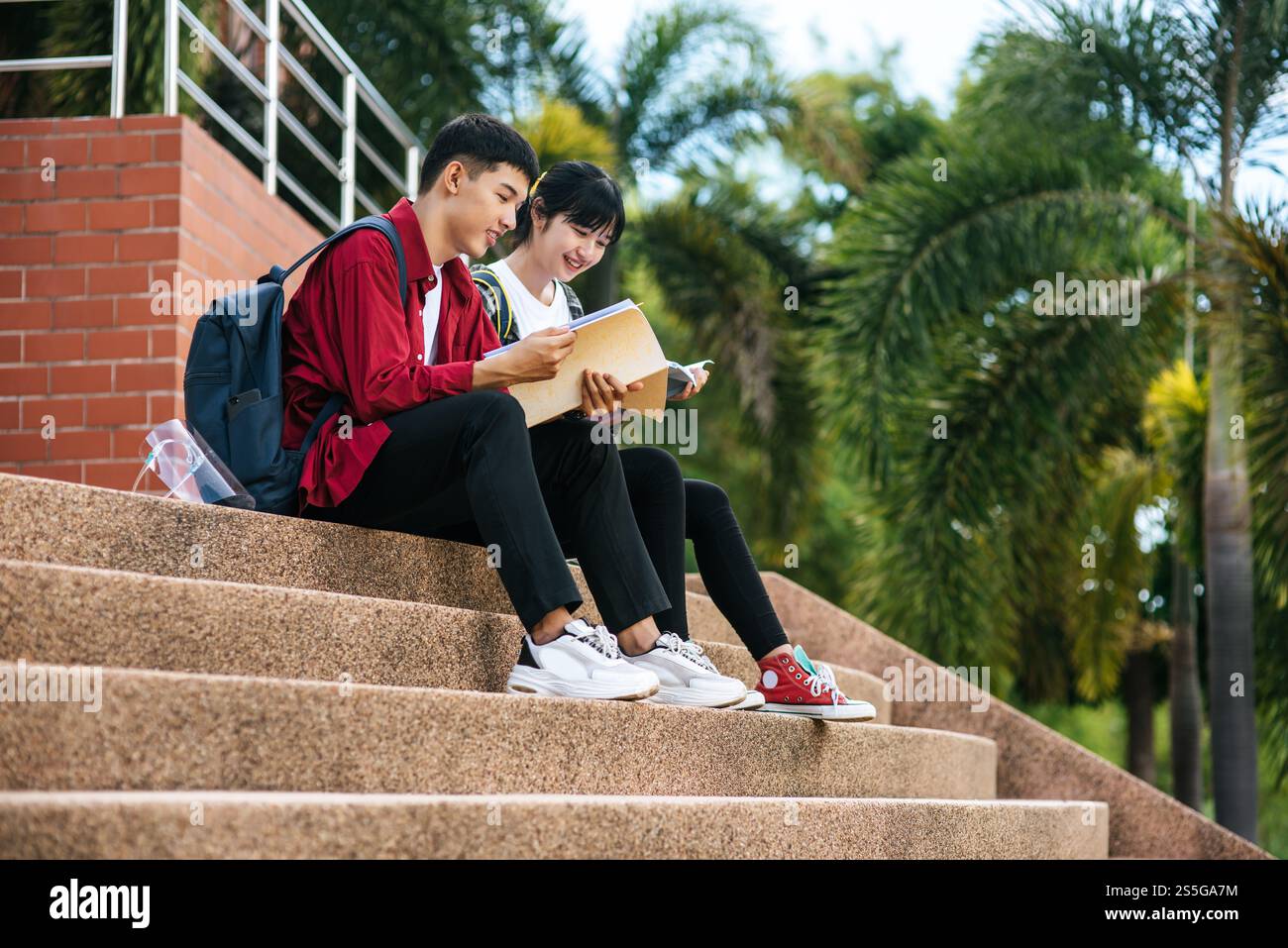 Male and female students sitting and reading books on the stairs Stock ...