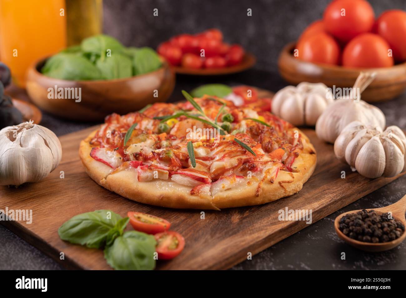 Pizza placed on a wooden plate complete with pepper seeds. Tomatoes and garlic. Selective focus. Stock Photo