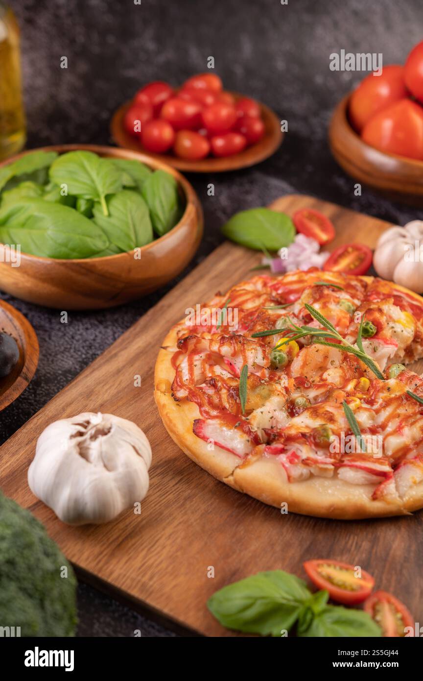 Pizza placed on a wooden plate complete with pepper seeds. Tomatoes and garlic. Selective focus. Stock Photo