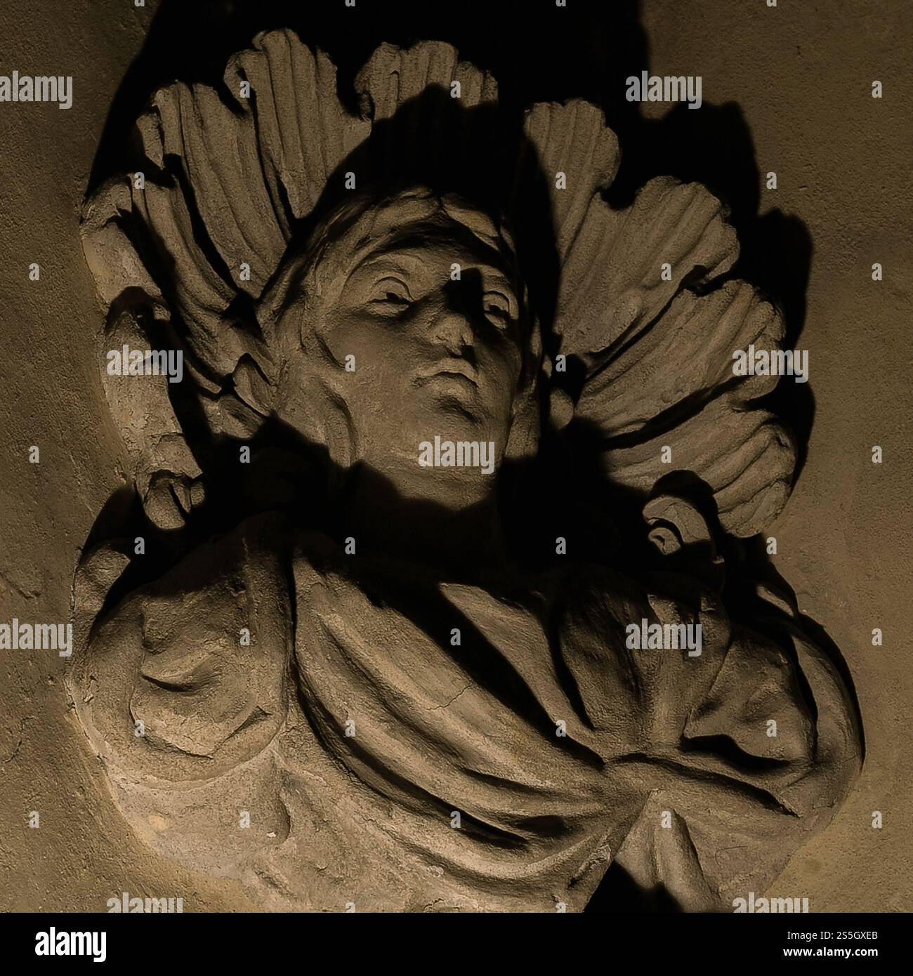 Staring upwards: dark shadows cast by an uplighter add drama and mystery to this late-18th century portrait bust corbel supporting the cloister ceiling vault in the Zlatá Koruna or Golden Crown Cistercian monastery in South Bohemia, Czechia / Czech Republic.  The cloister was revamped and redecorated in the late-1700s with Baroque and Rococo frescoes and stucco. Stock Photo