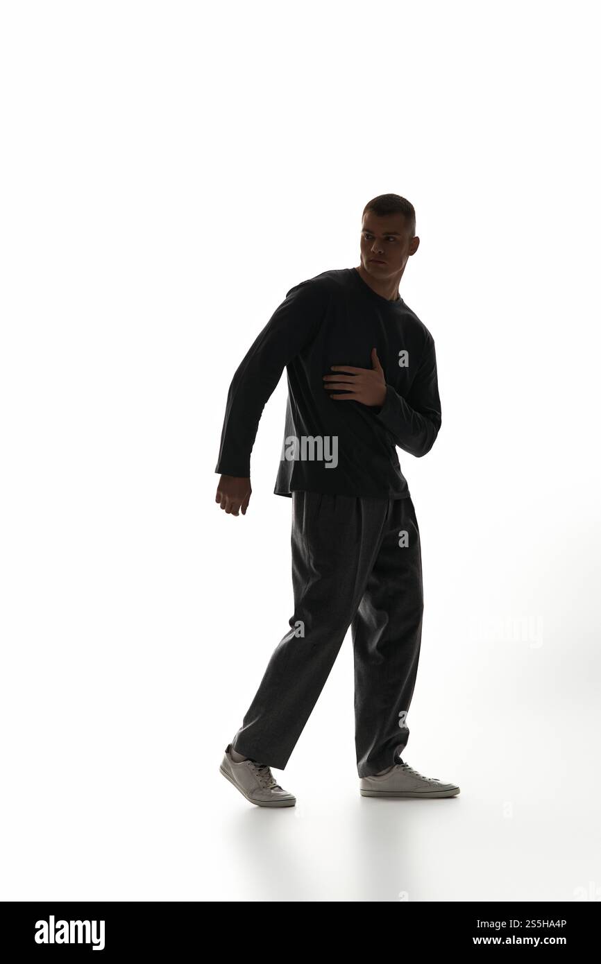 A handsome young man strikes a dynamic pose against a bright, minimal ...