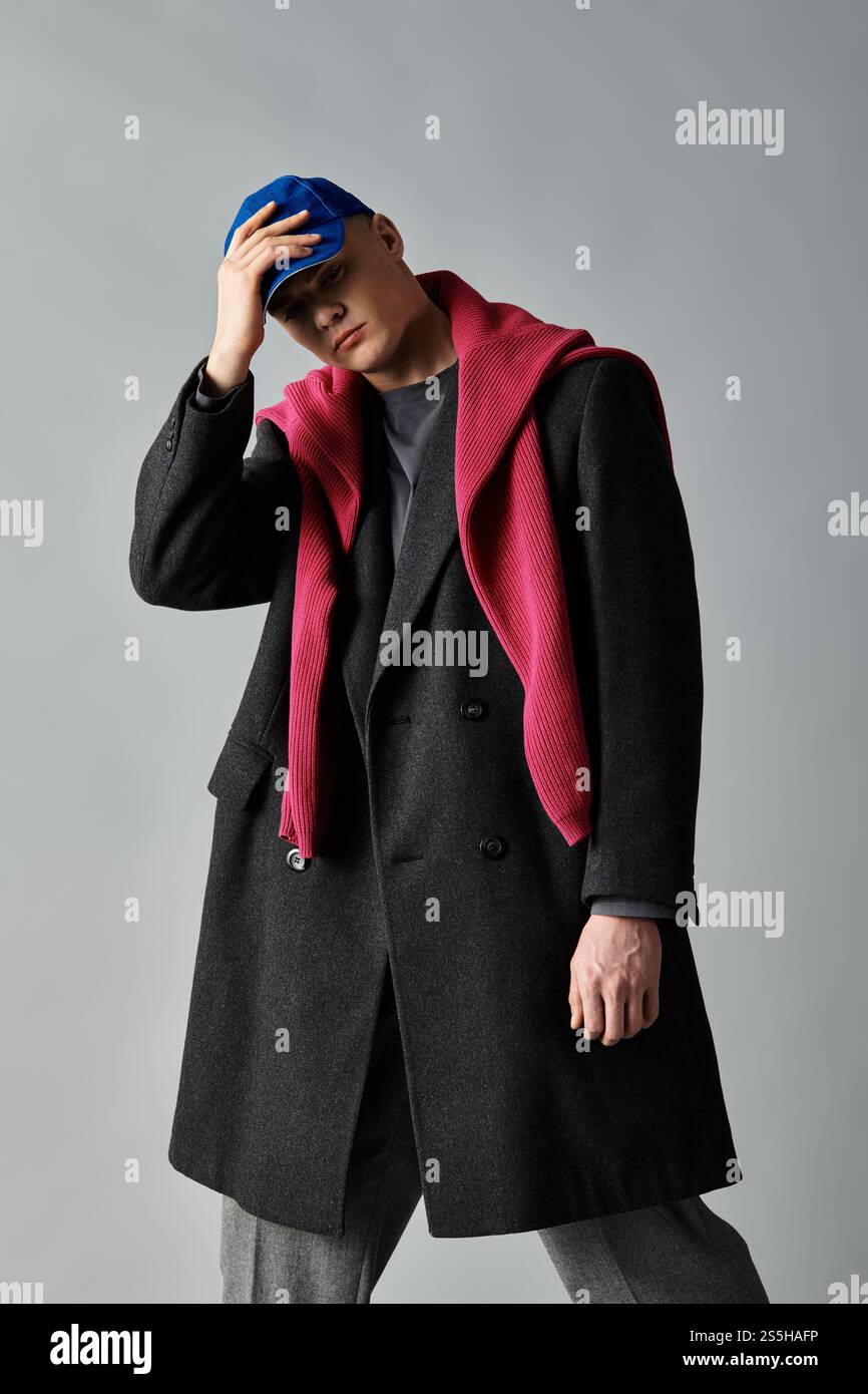A young man confidently wears a stylish coat and vibrant scarf in a ...