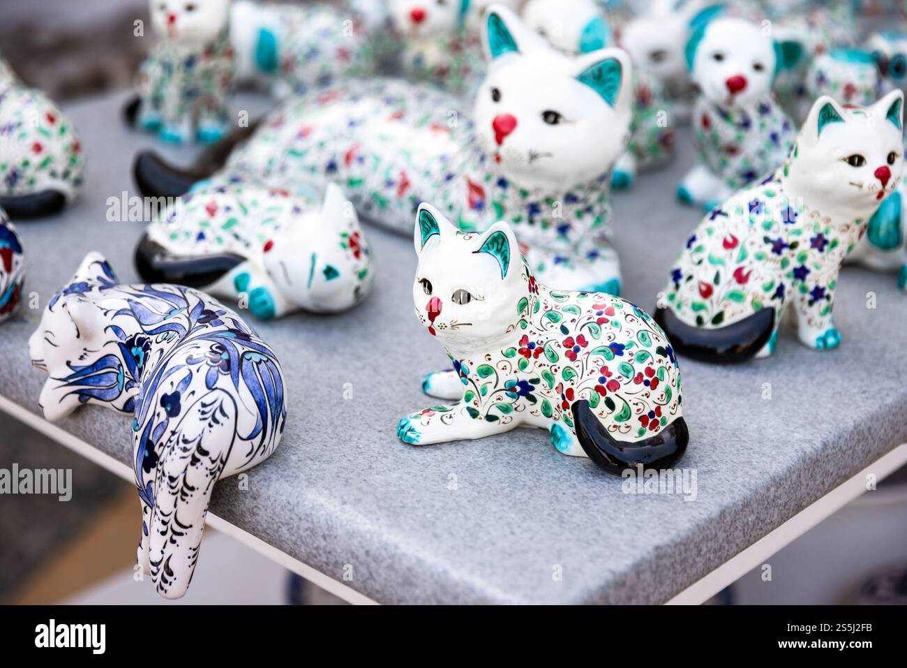 White ceramic cats with oriental patterns are on a counter of souvenir ...