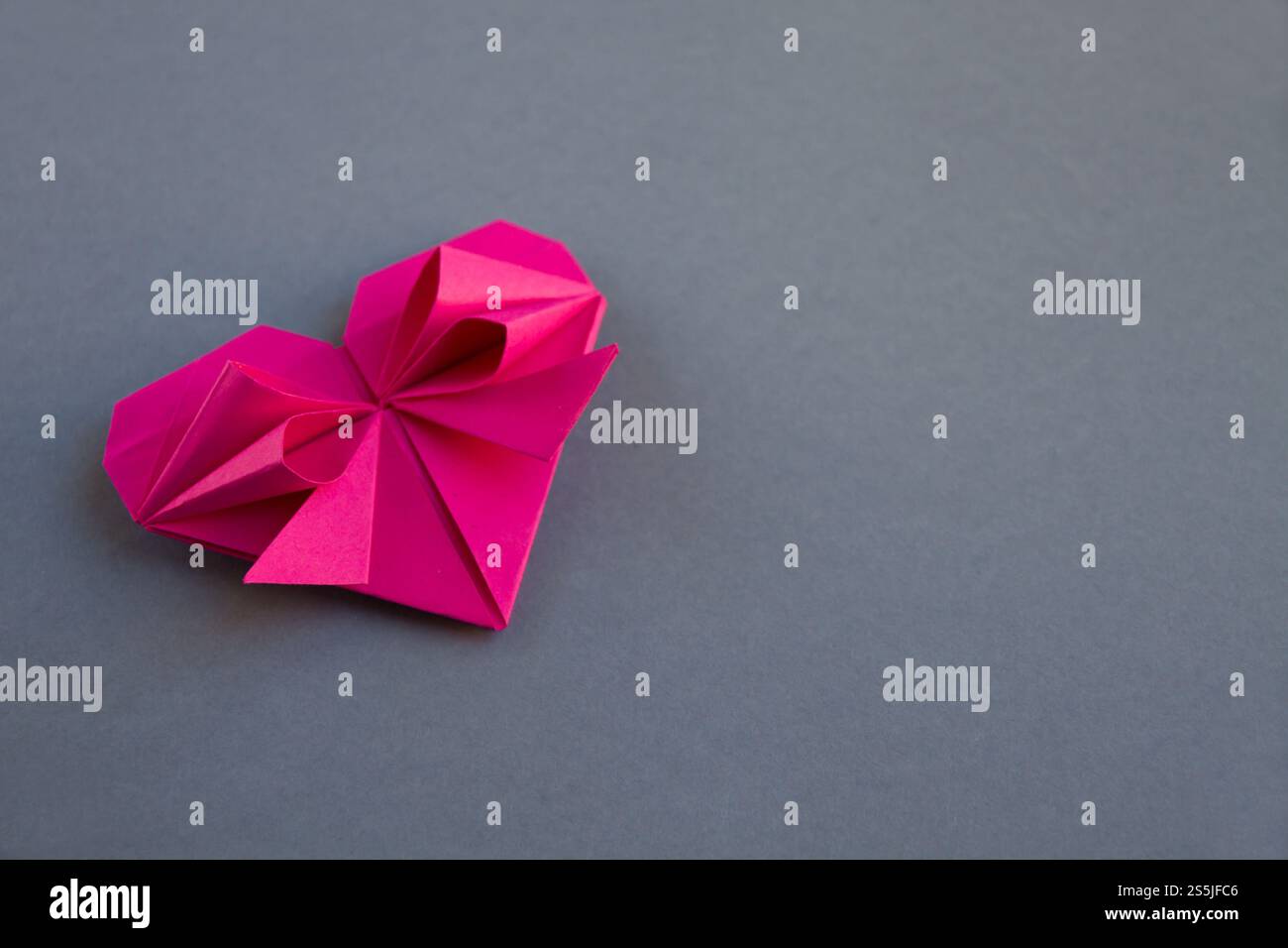Pink paper heart origami isolated on a blank grey background ...