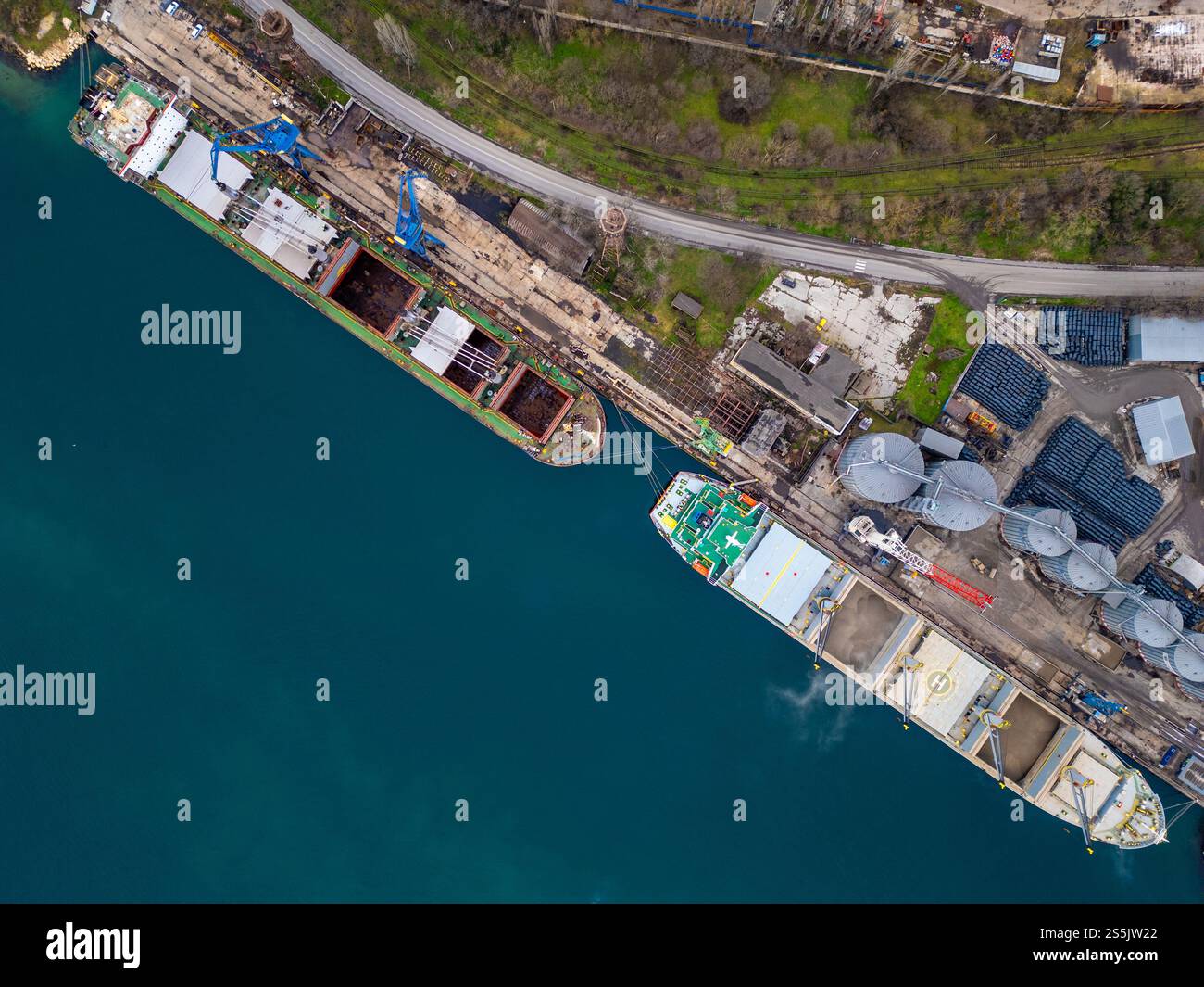 Wide aerial view of two cargo ships docked side by side at a bustling ...