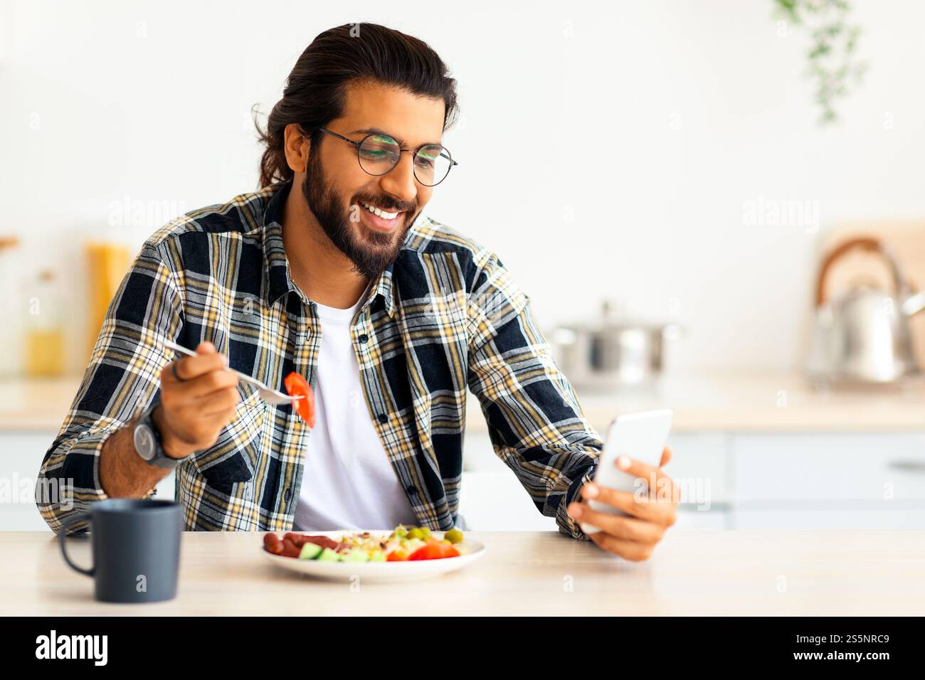 Handsome arab man using cellphone while having breakfast Stock Photo