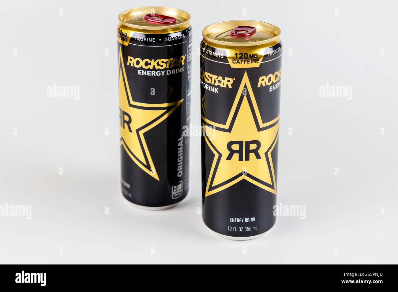 Energy drink cans featuring bold star design in black and gold with high caffeine content displayed against neutral backdrop Stock Photo