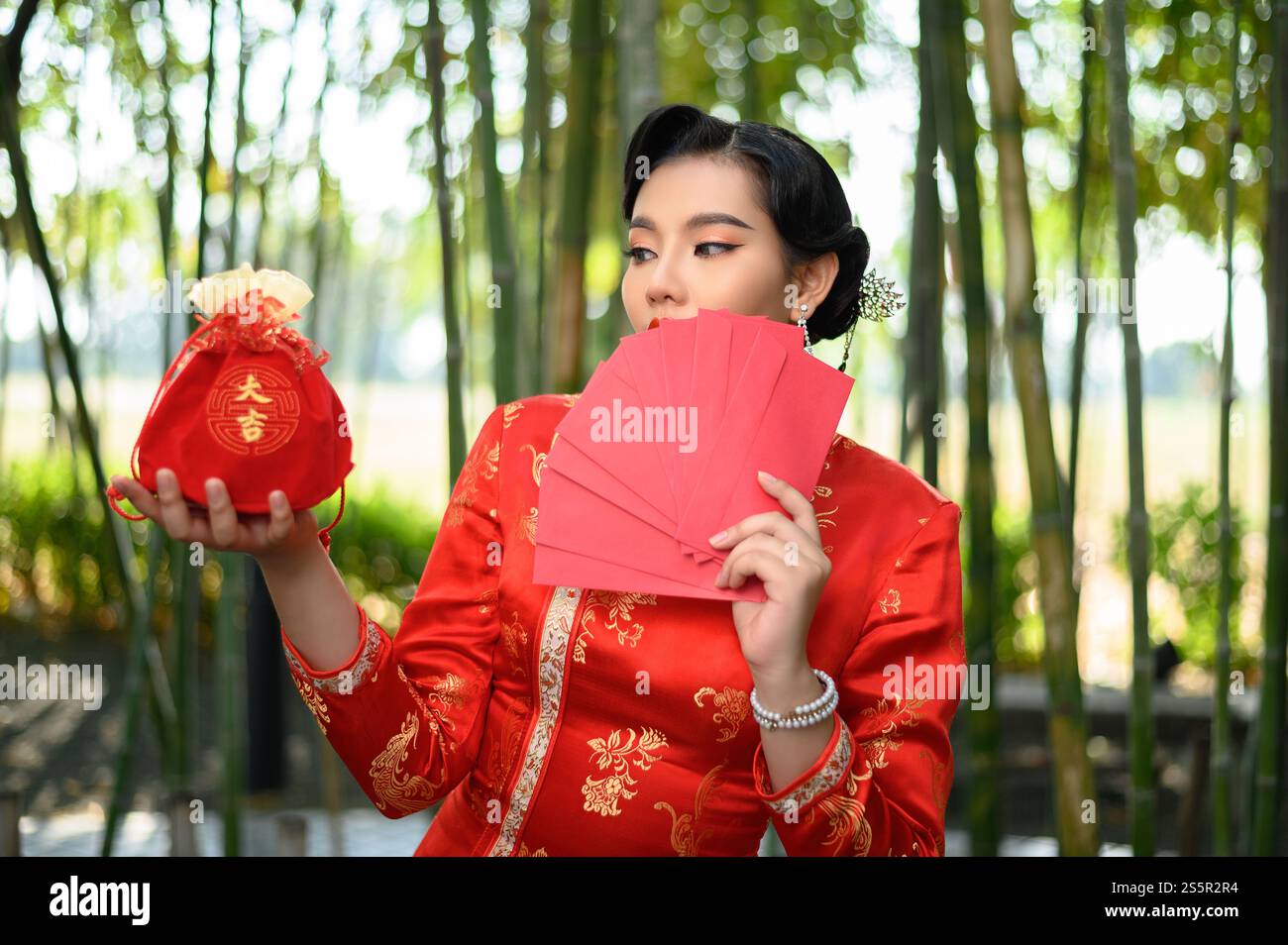 Portrait pretty Asian woman in a Chinese cheongsam posing envelopes fan ...