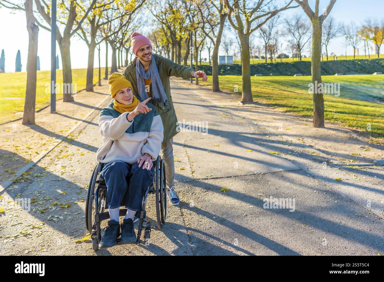 Two friends are walking in a park, one is using a wheelchair and they ...
