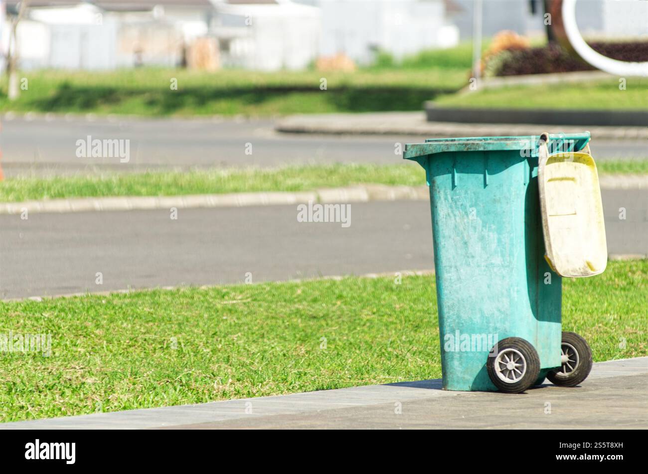 Blue Trash Bin on Sidewalk in Suburban Neighborhood on a Sunny Day Stock Photo