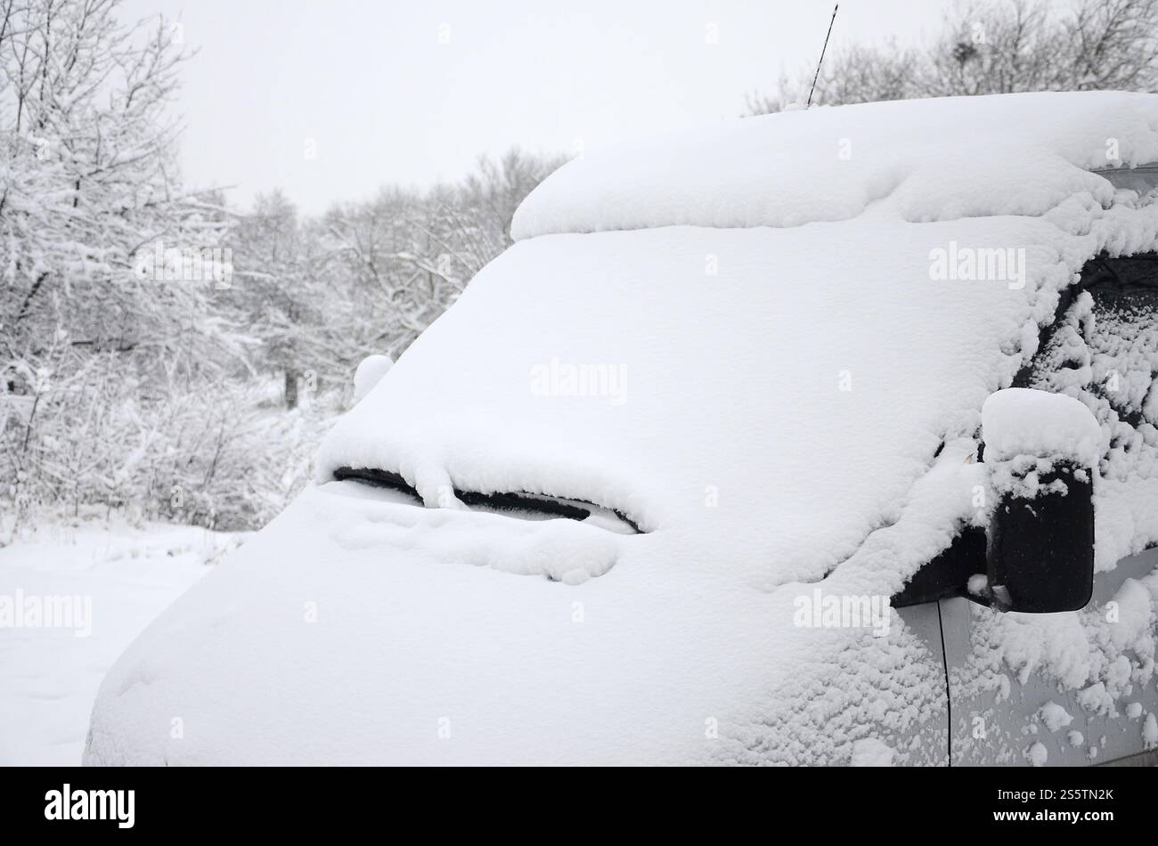 Fragment of the car under a layer of snow after a heavy snowfall. The body of the car is covered with white snow Stock Photo