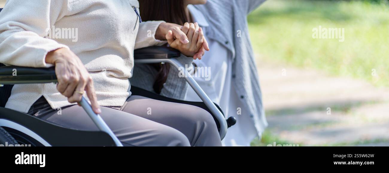 Asian senior woman in wheelchair with happy daughter. Family relationship retired woman sitting on wheelchair in the park age care at retirement home Stock Photo