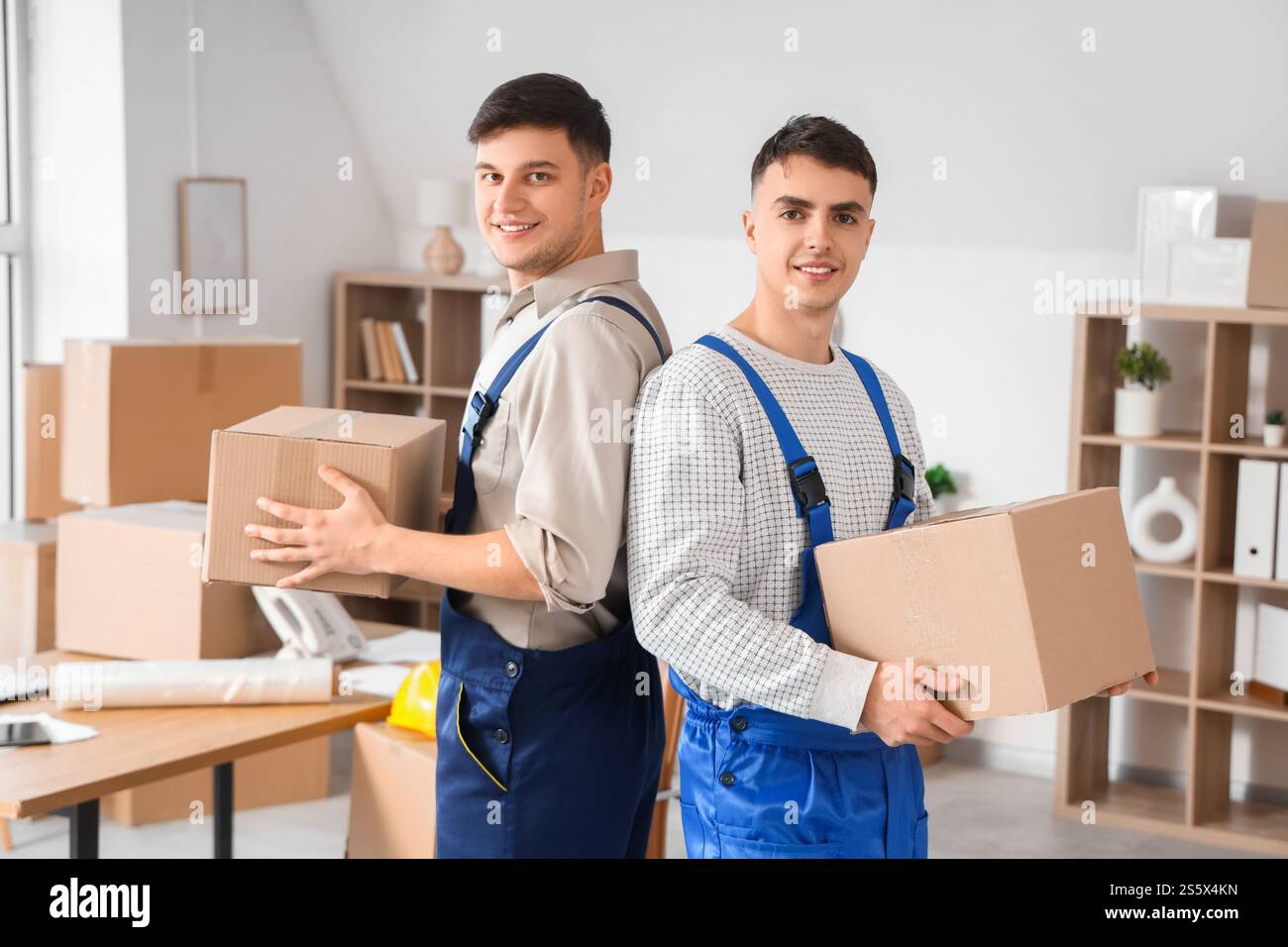 Male loaders with cardboard boxes in office Stock Photo - Alamy