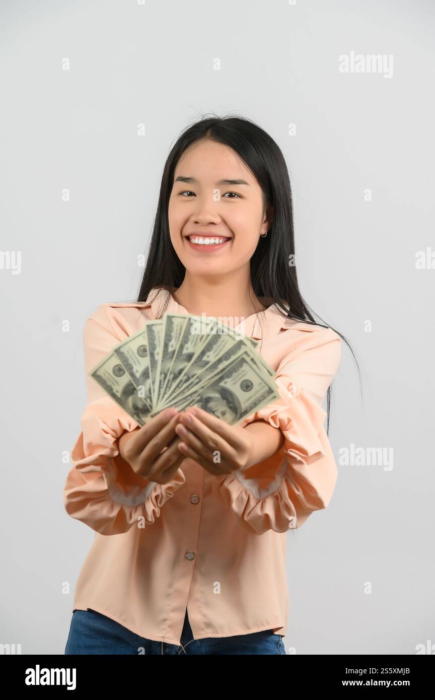 Portrait of a cheerful young woman holding money banknotes and ...