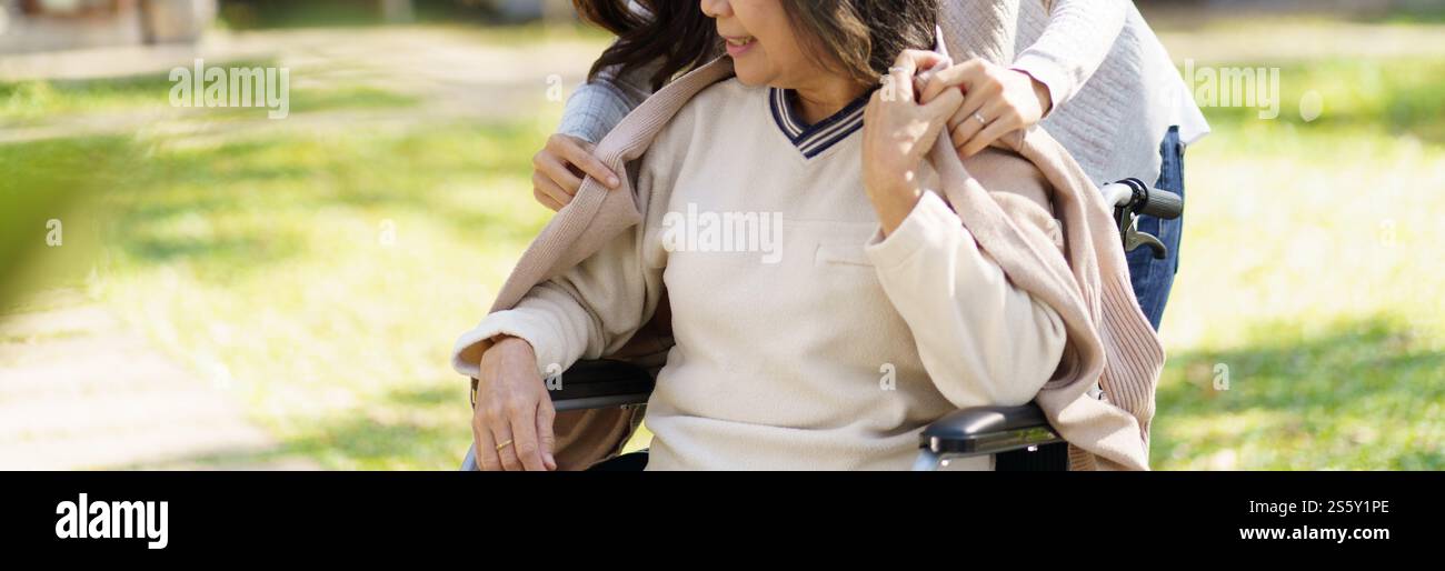 Asian senior woman in wheelchair with happy daughter. Family relationship retired woman sitting on wheelchair in the park age care at retirement home Stock Photo