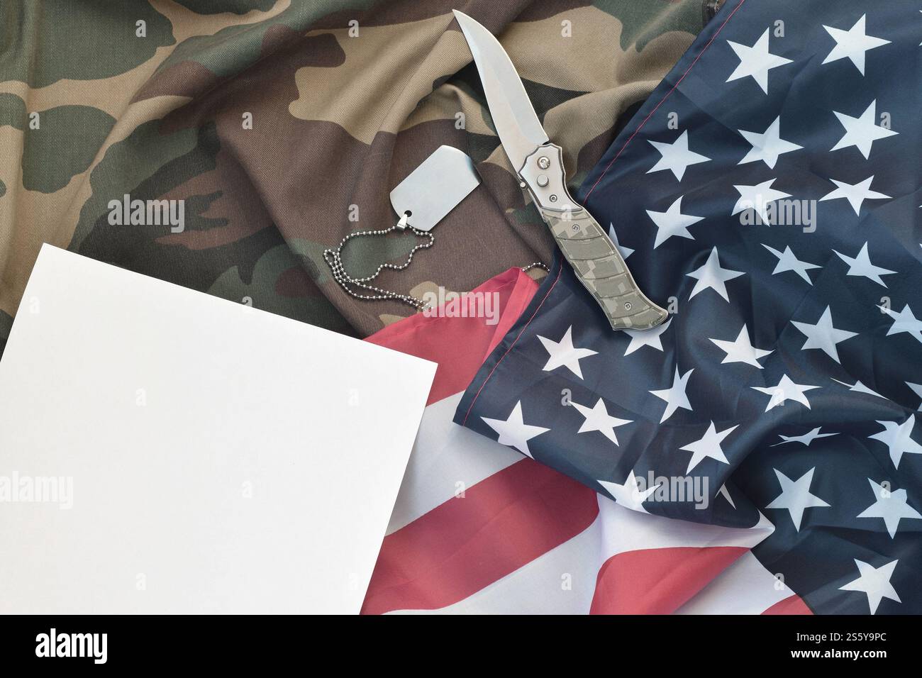 Blank paper lies with knife and army dog tag necklace on camouflage ...