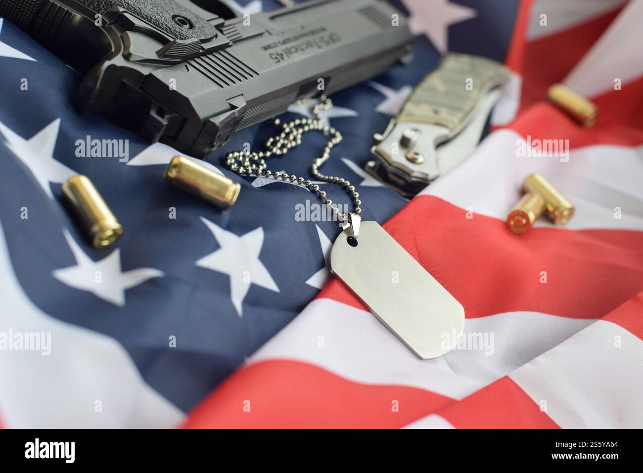 Army Dog tag token with 9mm bullets and pistol lie on folded United ...