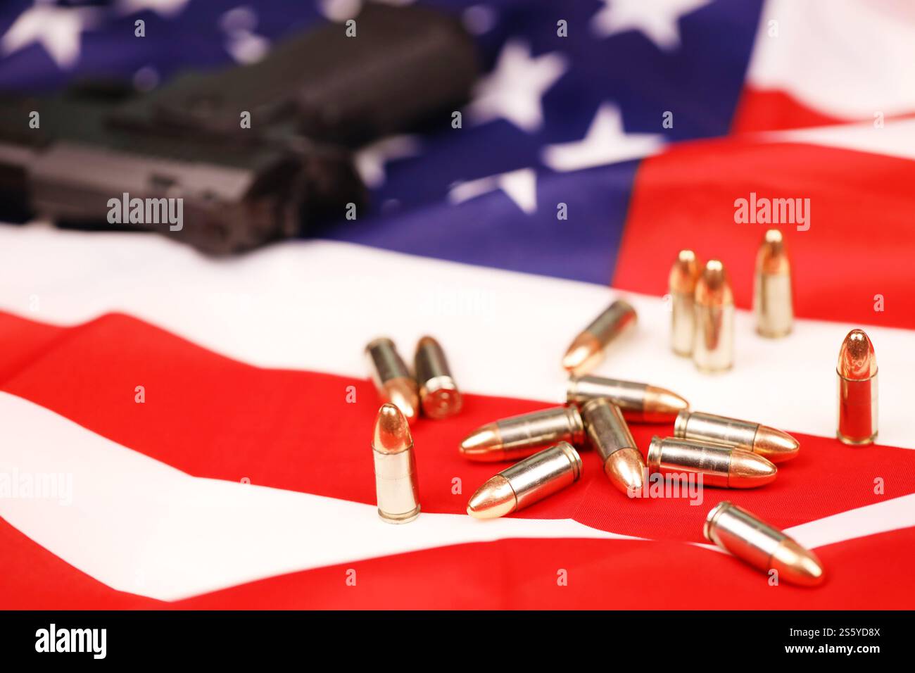 Many yellow 9mm bullets and gun on United States flag. Concept of gun trafficking on USA territory or US shooting range. Many yellow 9mm bullets and Stock Photo