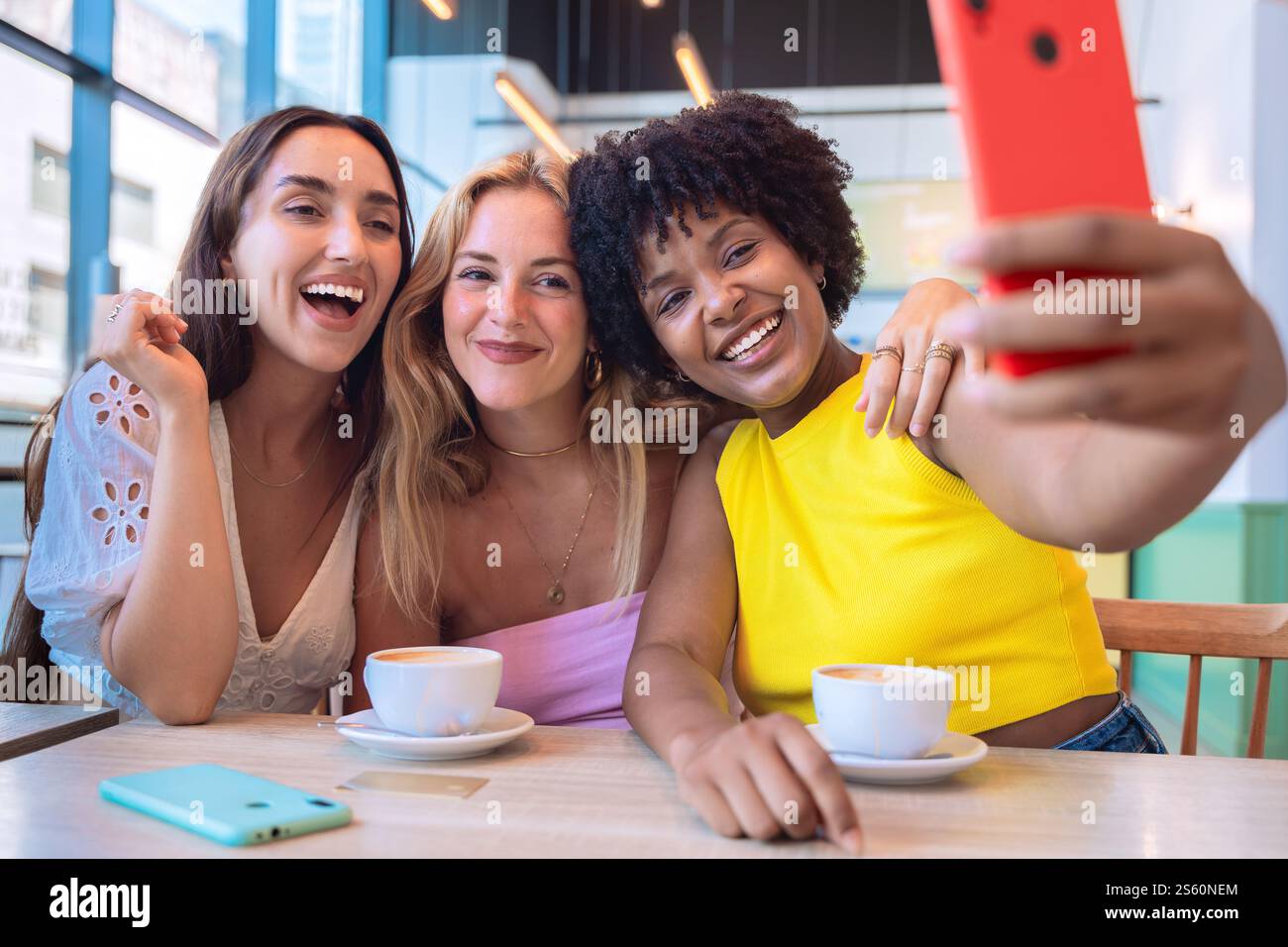Three happy Friends Taking a Selfie While Enjoying Coffee in a Modern Cafe Stock Photo