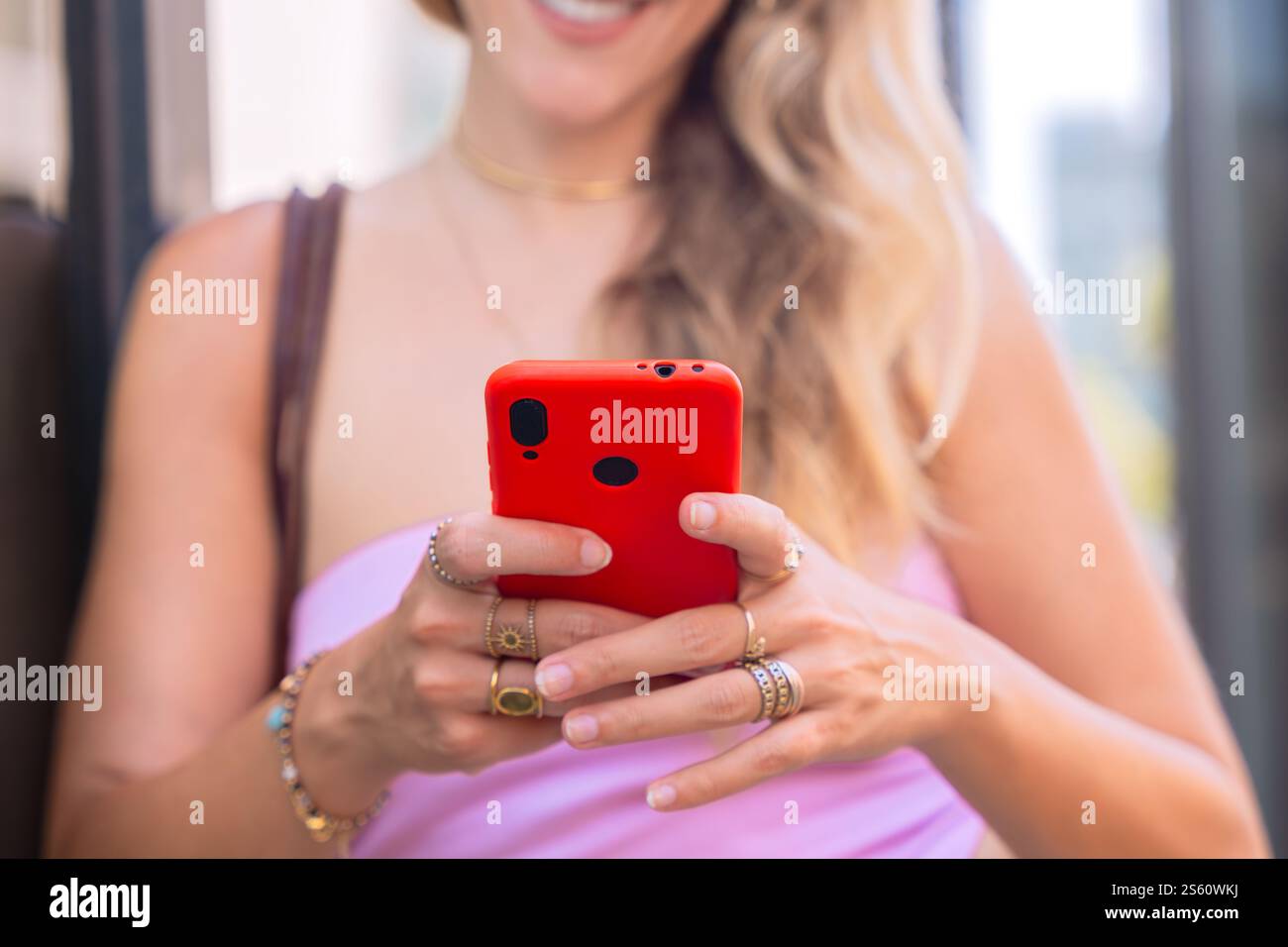 Unrecognizable Blonde Woman Using Smartphone Outdoors in Urban Setting Stock Photo