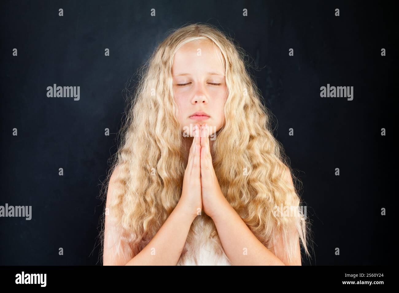 Cute young girl closed her eyes and praying. Hands folded in prayer ...