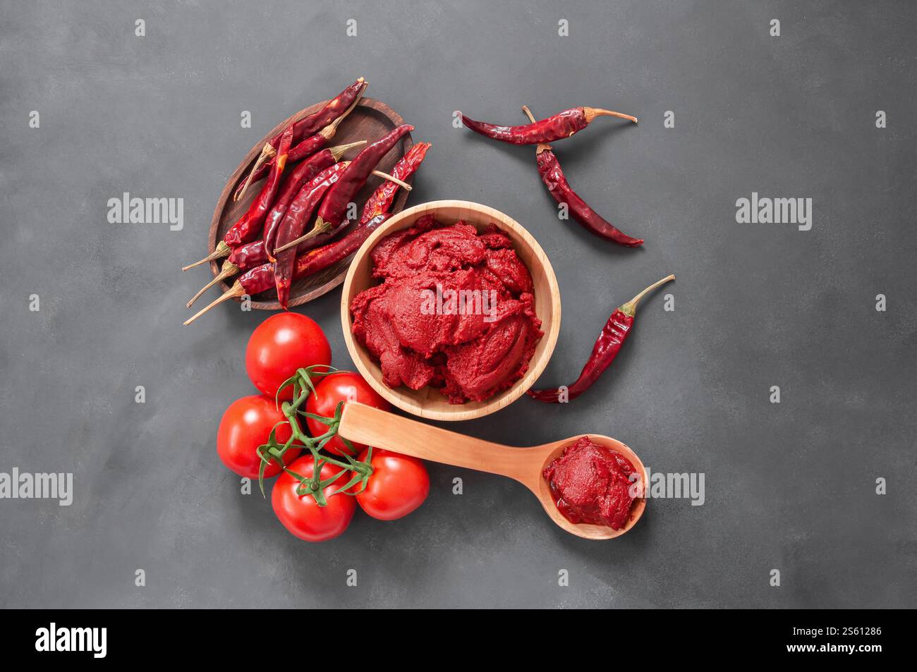 Traditional turkish chili pepper and tomato paste in bowl or spoon with dried peppers and fresh tomatoes on table Stock Photo