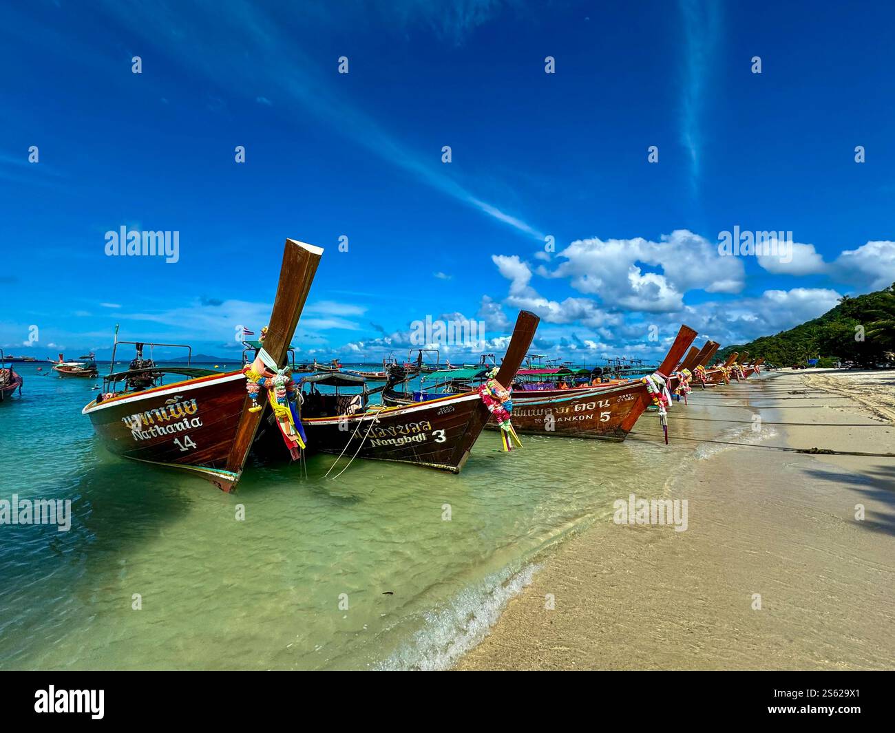 Long tail boats lined up on the beach in Phi Phi Island Thailand with dreamy sky - Smartphone Captured Stock Image