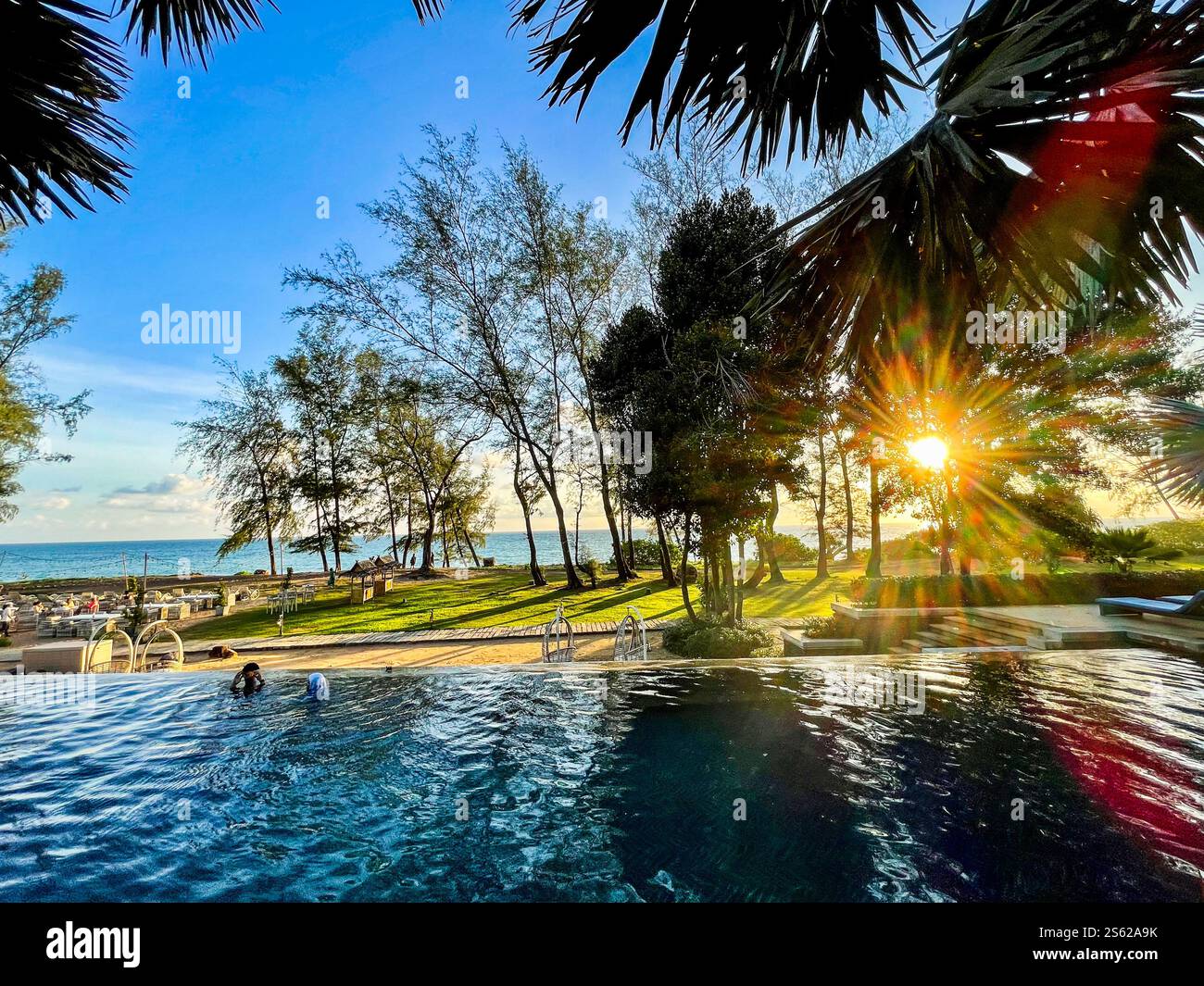 View over pool towards the sea, blue sky, smaal clouds and trees - Smartphone Captured Stock Image