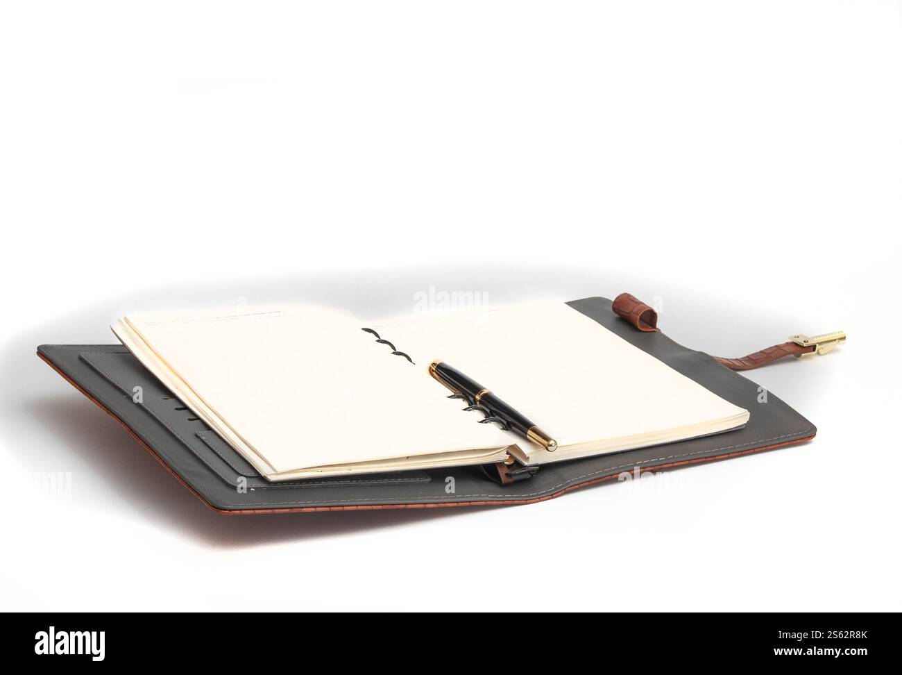 Opened notebook with a pen on a page on a white background. Stock Photo