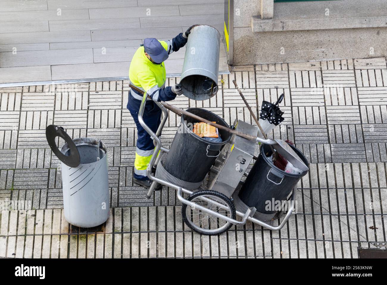 High angle view of a Cleaning worker emptying the trash into his cleaning cart on a city sidewalk Stock Photo