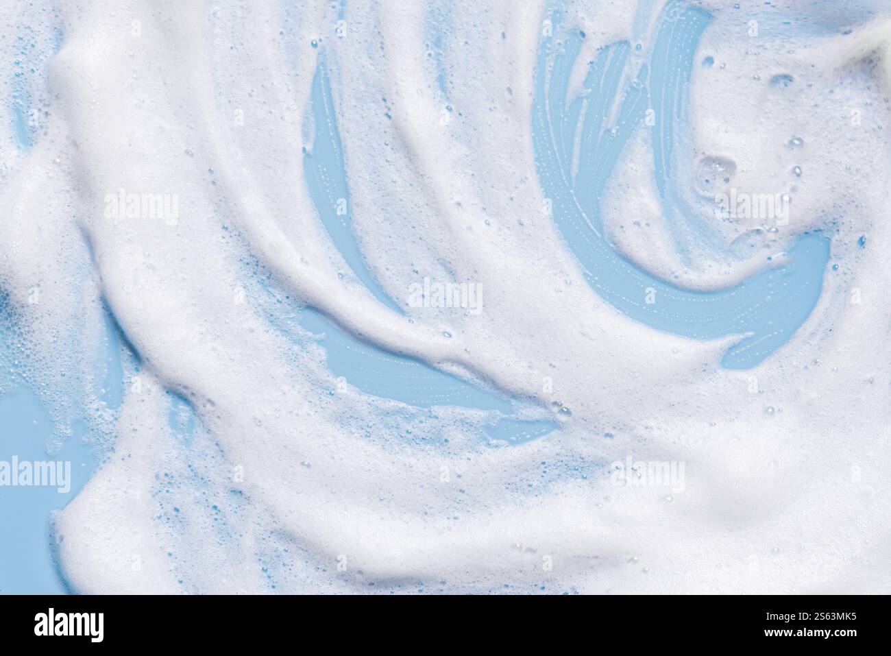 White soft foam texture swatch on blue pastel background. Face cleanser mousse sample, soap foam. Stock Photo