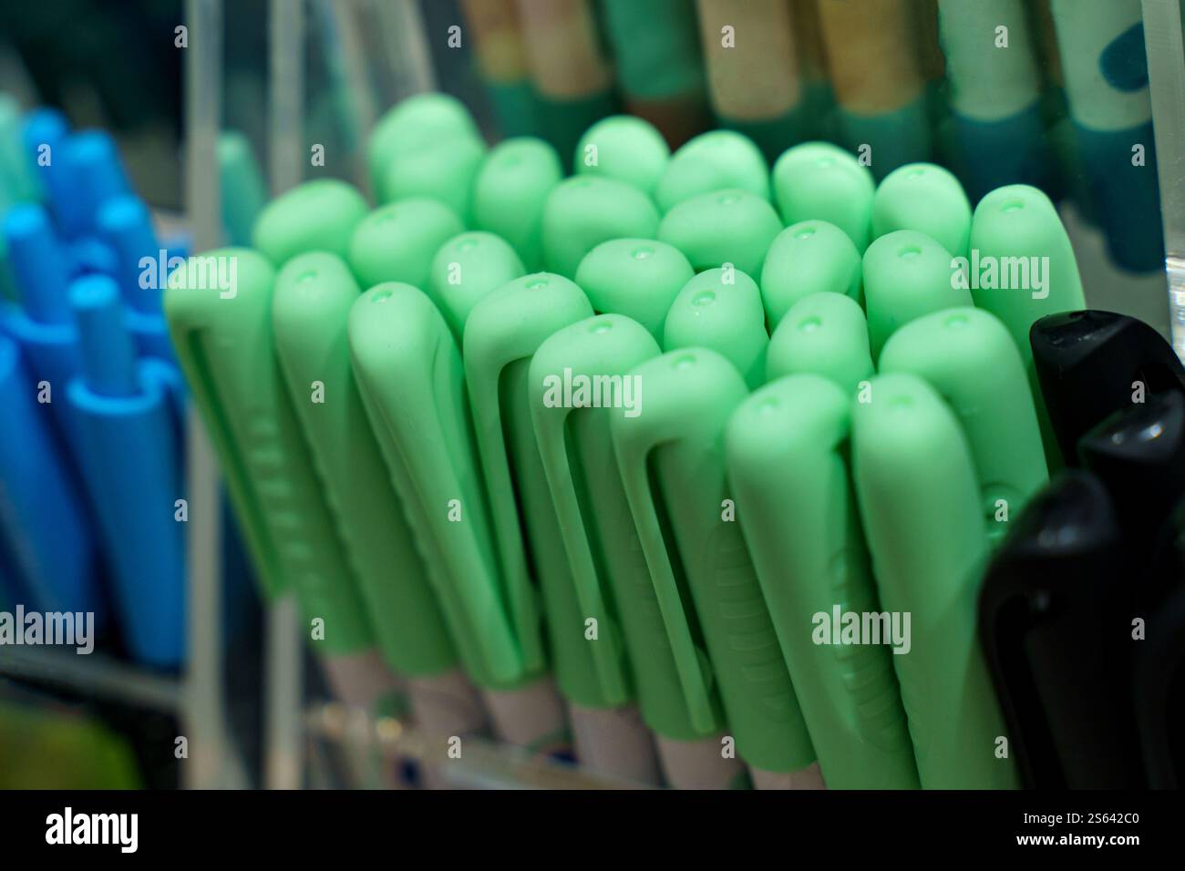 Rows of vibrant green pens rest in an organized manner on a display stand. The stationery collection showcases different shades and styles. Bright col Stock Photo