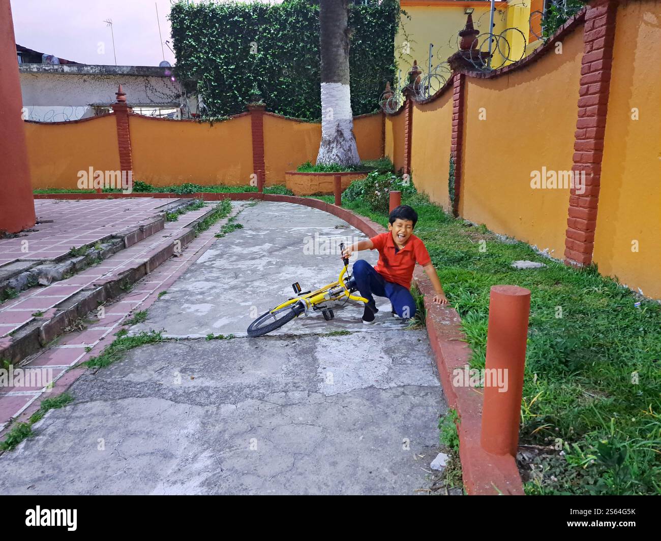 10-year-old dark-skinned Latino male child suffers a fall from his bicycle with pain in his legs and arms Stock Photo