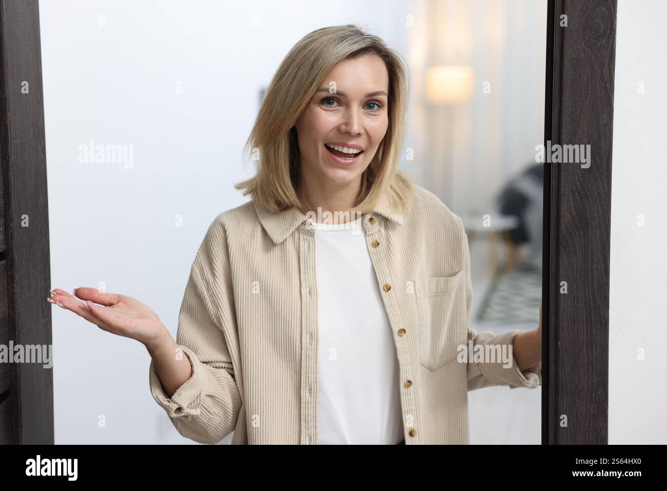 Cheerful woman welcoming guests to her apartment Stock Photo - Alamy
