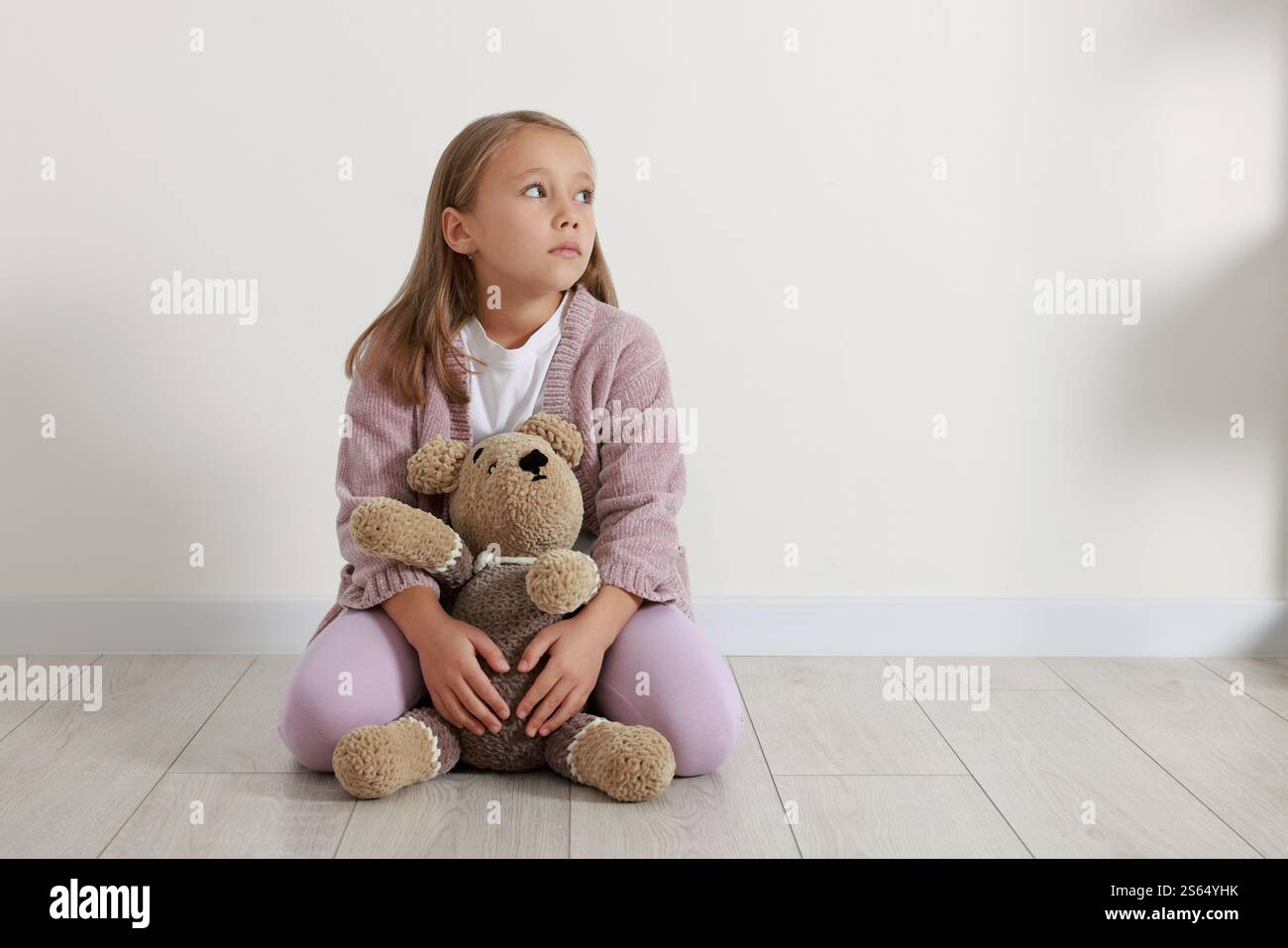 Autism concept. Lonely little girl with teddy bear on floor at home ...