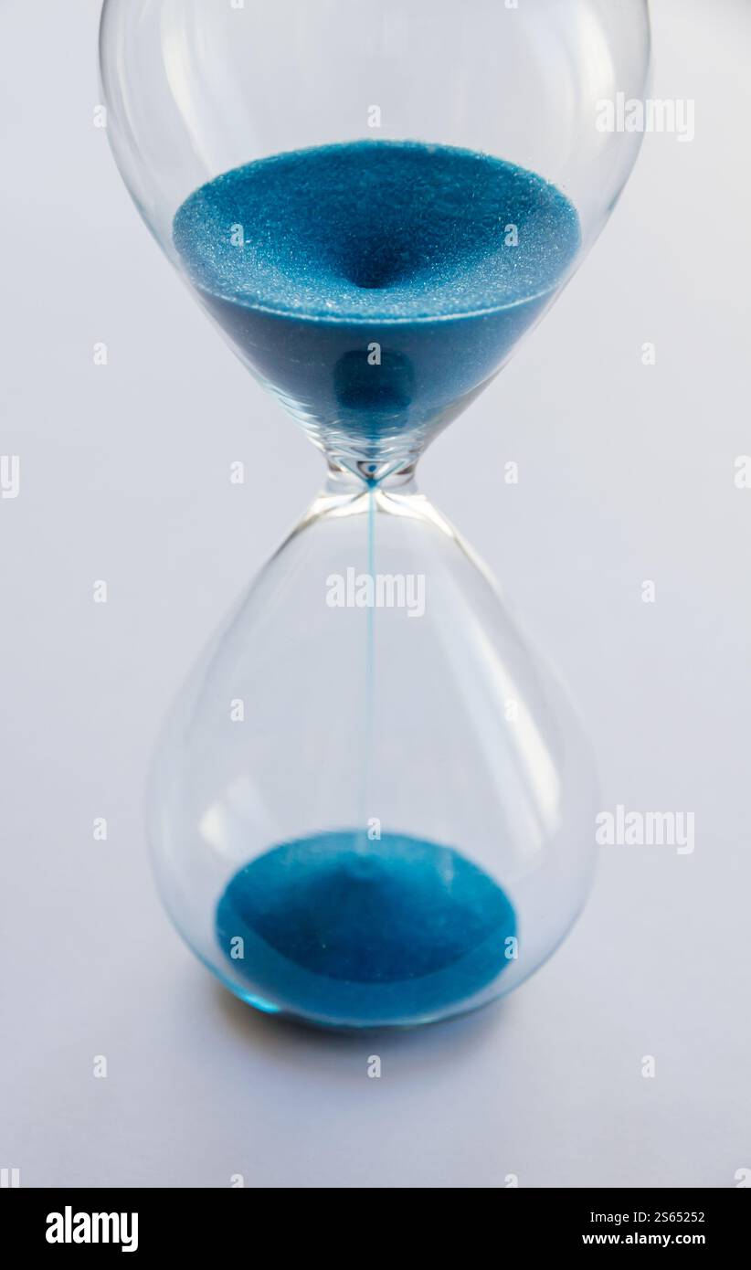 Hourglass containing blue sand isolated on white background. Concept of time passing. Hourglass containing blue sand isolated on white background Stock Photo