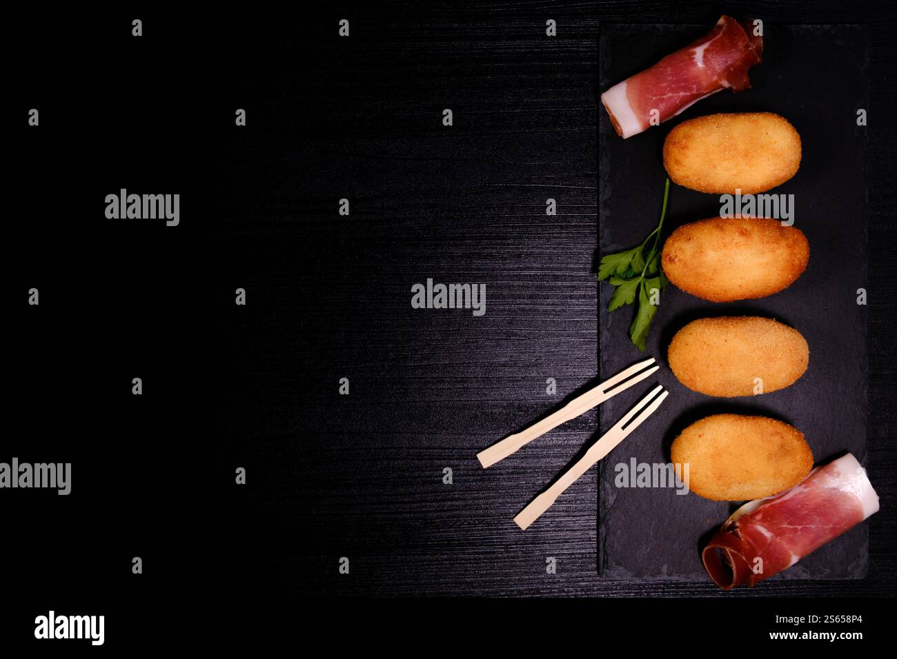 Croquettes with ham on rectangular slate plate with negative space on the left Stock Photo