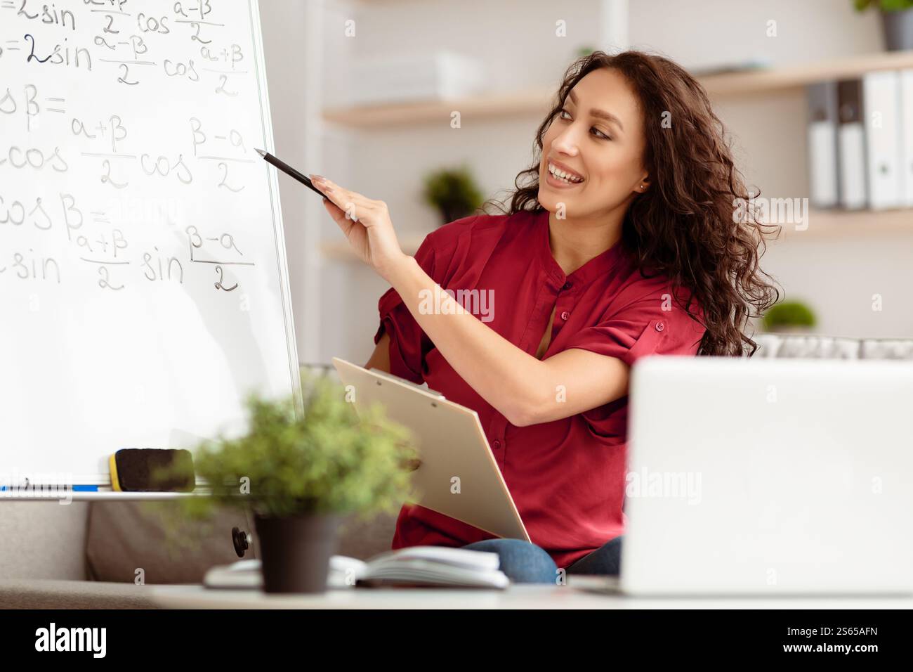 Lady teacher explaining math to students using pc Stock Photo
