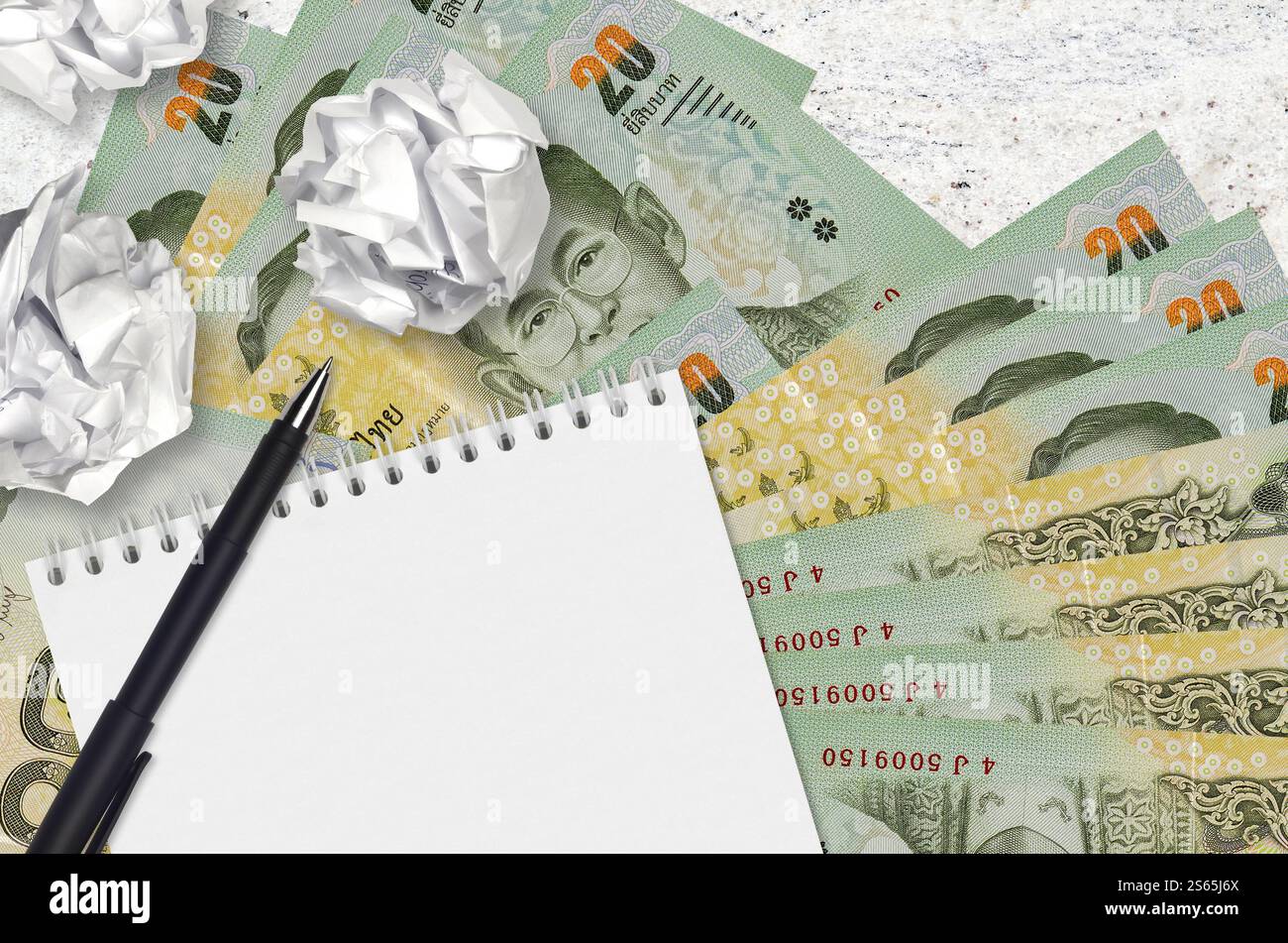 20 Thai Baht bills and balls of crumpled paper with notepad. Bad ideas ...